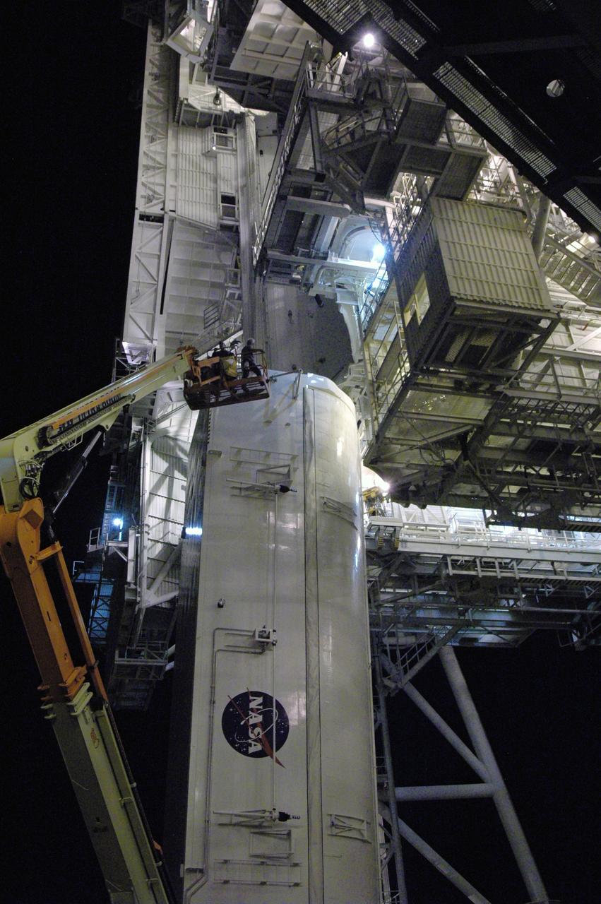 CAPE CANAVERAL, Fla. - On Launch Pad 39A at NASA's Kennedy Space Center, workers on the crane prepare to attach adjusted guide shoes onto the outside of the payload canister for a second lift to the payload changeout room. The first attempt encountered problems when Teflon pads on “shoes” attached to the outside of the canister that go onto guide rails to help the canister into the room didn’t fit properly. The two shoes were removed, slightly shaved down so that they would fit into the rails and put back on the canister. The changeout room is the enclosed, environmentally controlled portion of the rotating service structure that supports cargo delivery to the pad and subsequent vertical installation into the shuttle’s payload bay. Launch of Atlantis is targeted for Oct. 10. Photo credit: NASA/Jim Grossmann