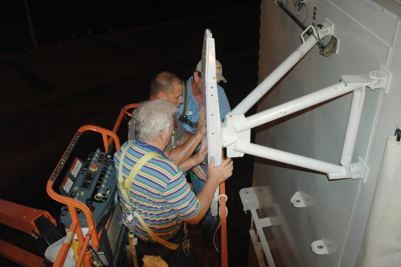 CAPE CANAVERAL, Fla. - On Launch Pad 39A at NASA's Kennedy Space Center, workers on a crane attach adjusted guide shoes onto the outside of the payload canister for attempt at a second lift to the payload changeout room. The first attempt encountered problems when Teflon pads on “shoes” attached to the outside of the canister that go onto guide rails to help the canister into the room didn’t fit properly. The two shoes were removed, slightly shaved down so that they would fit into the rails and put back on the canister. The changeout room is the enclosed, environmentally controlled portion of the rotating service structure that supports cargo delivery to the pad and subsequent vertical installation into the shuttle’s payload bay. Launch of Atlantis is targeted for Oct. 10. Photo credit: NASA/Jim Grossmann
