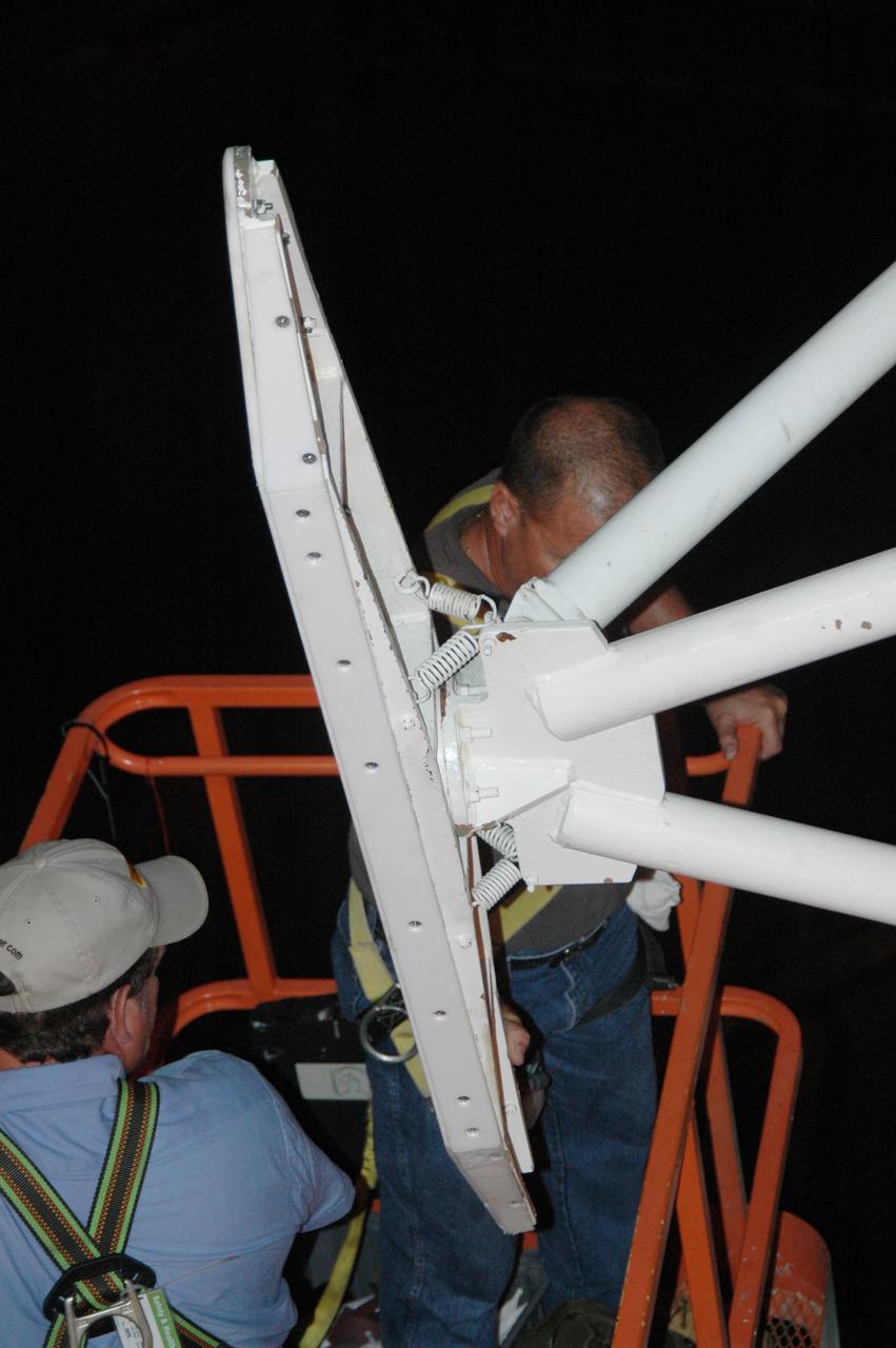 CAPE CANAVERAL, Fla. - On Launch Pad 39A at NASA's Kennedy Space Center, workers on a crane attach adjusted guide shoes onto the outside of the payload canister for attempt at a second lift into the payload changeout room. The first attempt encountered problems when Teflon pads on “shoes” attached to the outside of the canister that go onto guide rails to help the canister into the room didn’t fit properly. The two shoes were removed, slightly shaved down so that they would fit into the rails and put back on the canister. The changeout room is the enclosed, environmentally controlled portion of the rotating service structure that supports cargo delivery to the pad and subsequent vertical installation into the shuttle’s payload bay. Launch of Atlantis is targeted for Oct. 10. Photo credit: NASA/Jim Grossmann