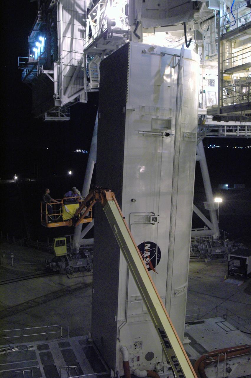 CAPE CANAVERAL, Fla. - On Launch Pad 39A at NASA's Kennedy Space Center, workers on a crane have completed attaching adjusted guide shoes onto the outside of the payload canister for attempt at a second lift into the payload changeout room. The first attempt encountered problems when Teflon pads on “shoes” attached to the outside of the canister that go onto guide rails to help the canister into the room didn’t fit properly. The two shoes were removed, slightly shaved down so that they would fit into the rails and put back on the canister. The changeout room is the enclosed, environmentally controlled portion of the rotating service structure that supports cargo delivery to the pad and subsequent vertical installation into the shuttle’s payload bay. Launch of Atlantis is targeted for Oct. 10. Photo credit: NASA/Jim Grossmann