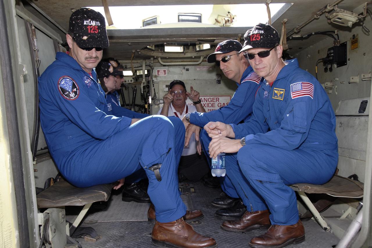 CAPE CANAVERAL, Fla. -  The STS-125 crew members listen to instructions for driving the M-113 armored personnel carrier.  From left are Mission Specialists John Grunsfeld, Megan McArthur, Michael Good, Mike Massimino and Gregory C. Johnson. The crew members of space shuttle Atlantis' STS-125 mission will each practice driving the M-113 in turn as part of their training on emergency egress procedures. An M-113 will be available to transport the crew to safety in the event of a contingency on the pad before their launch. The crew is at NASA's Kennedy Space Center for a dress launch rehearsal called the terminal countdown demonstration test, or TCDT. It provides astronauts and ground crews with an opportunity to participate in various simulated countdown activities, including equipment familiarization,  emergency training and a simulated launch countdown. The STS-125 mission aboard space shuttle Atlantis to service NASA’s Hubble Space Telescope is targeted to launch Oct. 10.    Photo credit: NASA/Kim Shiflett