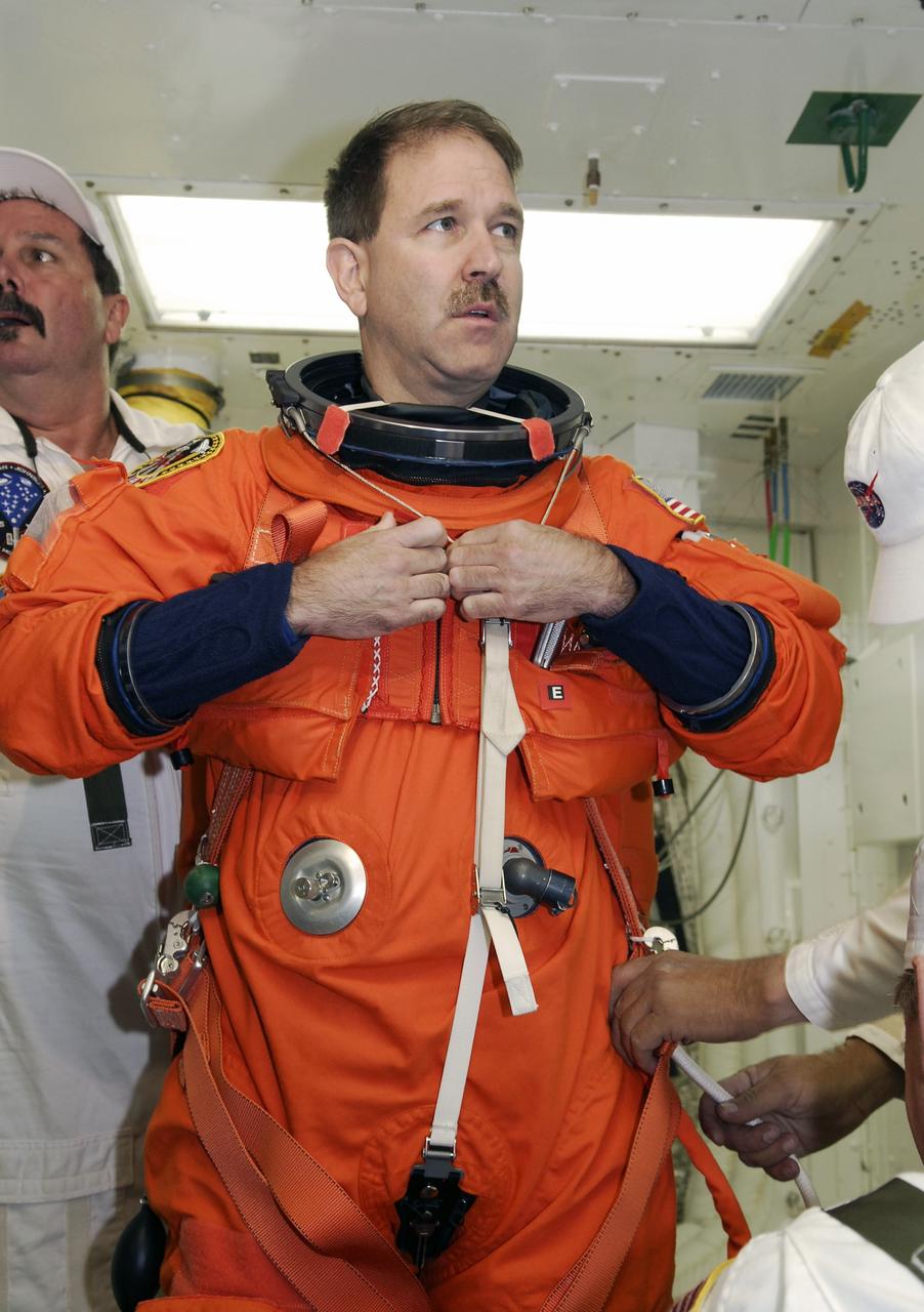 CAPE CANAVERAL, Fla. - STS-125 Mission Specialist John Grunsfeld is helped donning a harness over his launch and entry suit before entering space shuttle Atlantis for a simulated launch countdown. The countdown is the culmination of terminal countdown demonstration test, or TCDT, activities as preparation before launch. TCDT provides astronauts and ground crews with an opportunity to participate in various launch activities, including equipment familiarization, emergency training and the countdown. Atlantis’ STS-125 mission to service NASA’s Hubble Space Telescope is targeted for launch Oct. 14. Photo credit: NASA/Amanda Diller