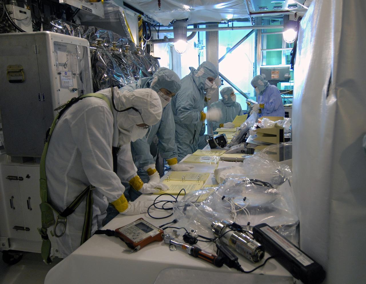 CAPE CANAVERAL, Fla. -   At NASA's Kennedy Space Center in Florida, workers check data on the payload ground handling mechanism, or PGHM, in the Payload Changeout Room on Launch Pad 39A.  The PGHM is being used to transfer the STS-125 mission payload into space shuttle Atlantis’ payload bay. STS-125 is the fifth and final shuttle servicing mission for NASA’s Hubble Space Telescope.  The payload comprises four carriers holding various equipment for the mission. Atlantis is targeted to launch Oct. 14 on the 11-day mission.  Photo credit: NASA/Jack Pfaller