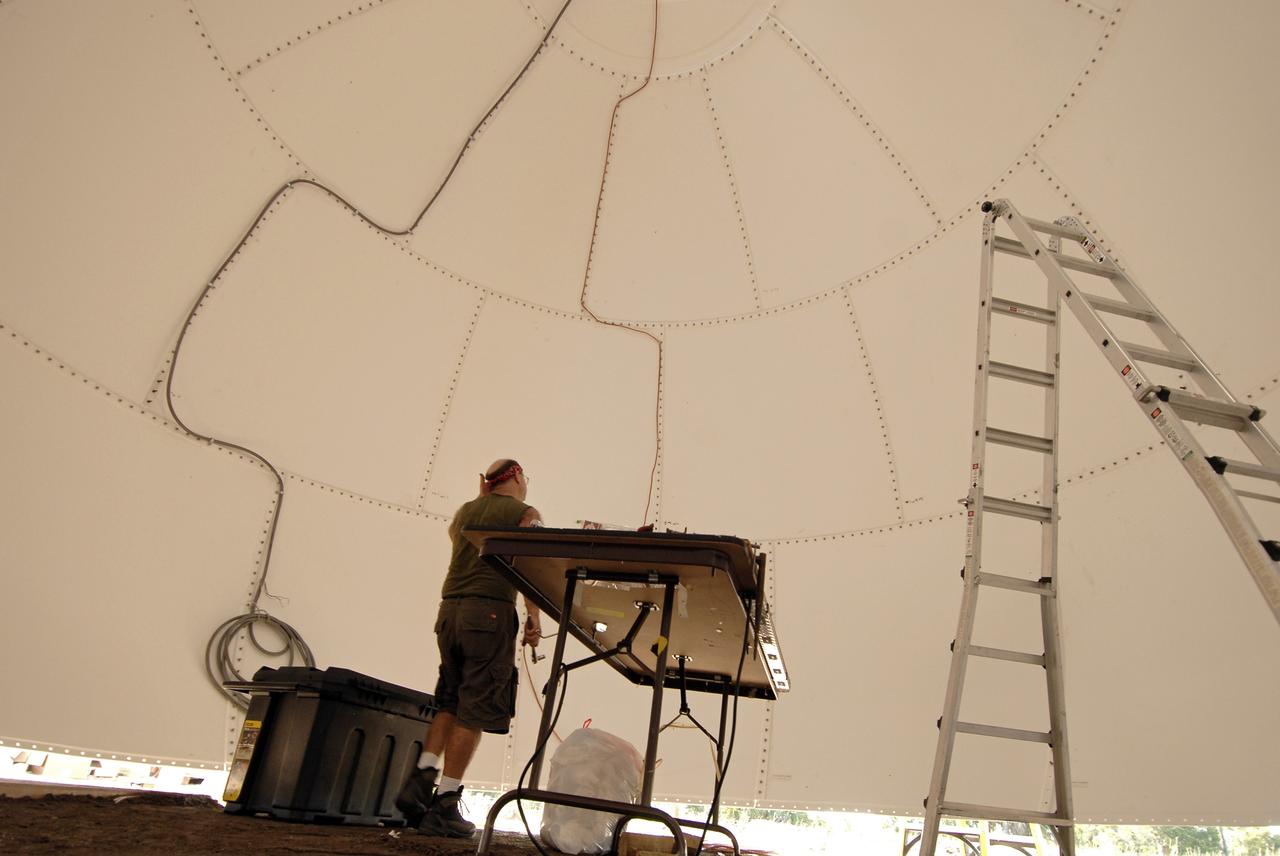 CAPE CANAVERAL, Fla. - A worker inside the radar dome, or radome, monitors equipment before it is lifted onto its base.  The dome is part of a new Doppler weather radar facility for the 45th Weather Squadron in an area near S.R. 520 in Orange County, Florida, replacing one at Patrick Air Force Base.  It will be used by NASA's Kennedy Space Center, the 45th Space Wing and their customers. The site will be able to monitor weather conditions directly above the launch pads at Kennedy.  The weather radar is essential in issuing lightning and other severe weather warnings and vital in evaluating lightning launch commit criteria.  The new radar, replacing what was installed 25 years ago at Patrick Air Force Base, includes Doppler capability to detect winds and identify the type, size and number of precipitation particles.  The site is ideally distant from the launch pads and has unobstructed views of Cape Canaveral Air Force Station and Kennedy. The radar will be used by forecasters at the USAF 45th Weather Squadron. Photo credit: NASA/Troy Cryder