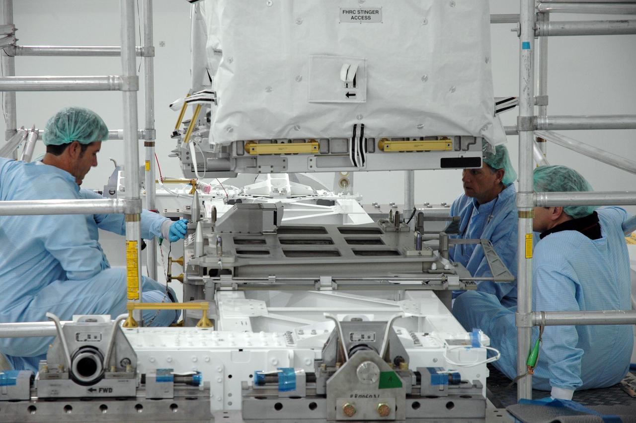 CAPE CANAVERAL, FIa. -- In the Space Station Processing Facility at NASA's Kennedy Space Center in Florida, workers supervise as an overhead crane lowers the flexible hose rotary coupler onto the Lightweight Multi-Purpose Experiment Support Structure Carrier for installation. The carrier will be installed in space shuttle Endeavour for the STS-126 mission to the International Space Station. The 15-day flight will deliver equipment and supplies to the space station in preparation for expansion from a three- to six-person resident crew aboard the complex. The mission also will include four spacewalks to service the station’s Solar Alpha Rotary Joints. Photo credit: NASA/Jim Grossmann