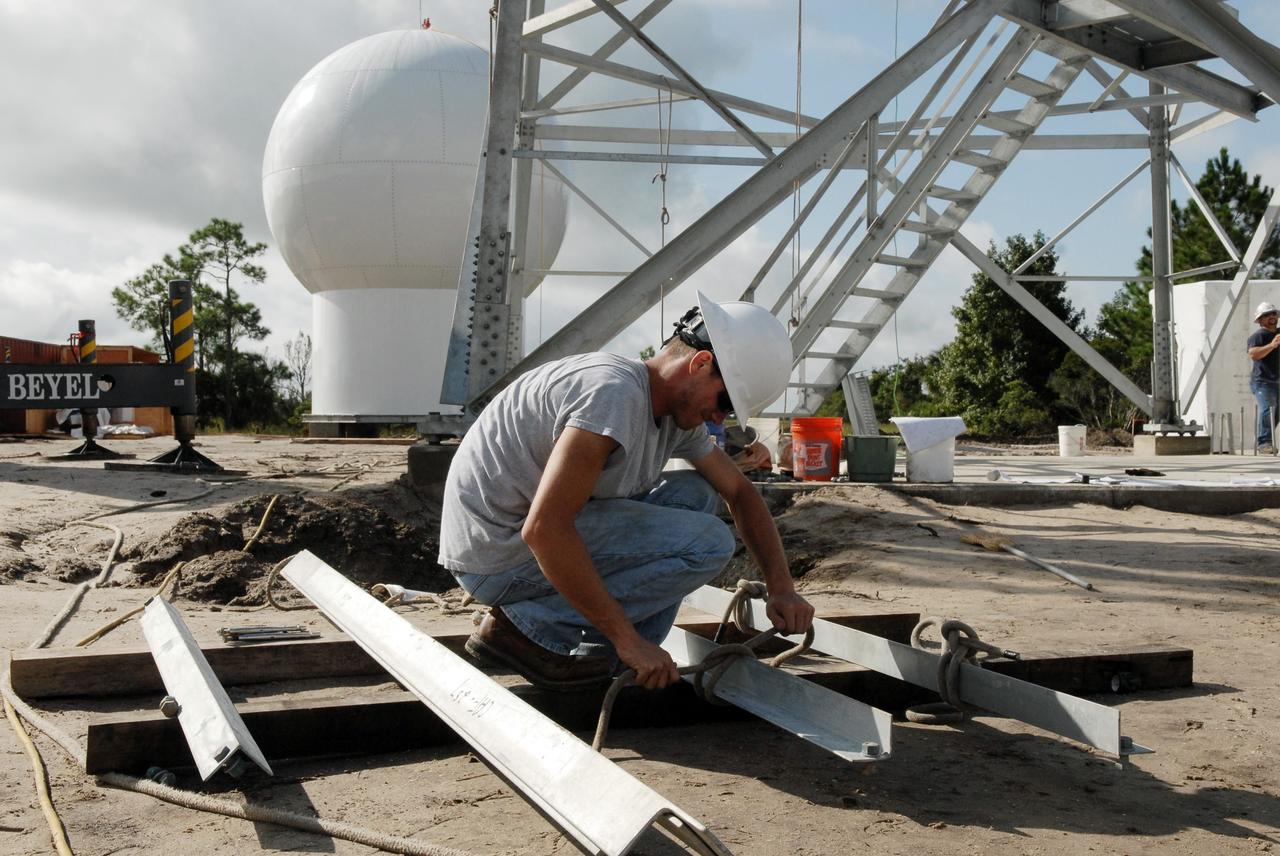CAPE CANAVERAL, Fla. – In an area near S.R. 520 in Orange County, Florida, a worker ties a line to a steel beam that will be added to a tower being constructed for a Doppler weather radar facility for the 45th Weather Squadron. In the background is the radome that will be on top of the tower.  The new site replaces one at Patrick Air Force Base. It will be used by NASA's Kennedy Space Center, the 45th Space Wing and their customers. The site will be able to monitor weather conditions directly above and surrounding the launch pads at Kennedy.  The weather radar is essential in issuing lightning and other severe weather warnings and vital in evaluating lightning launch commit criteria.  The new radar, replacing what was installed 25 years ago at Patrick Air Force Base, includes Doppler capability to detect winds and identify the type, size and number of precipitation particles.  The site is ideally distant from the launch pads and has unobstructed views of Cape Canaveral Air Force Station and Kennedy. The radar will be used by forecasters at the USAF 45th Weather Squadron. Photo credit: NASA/Troy Cryder