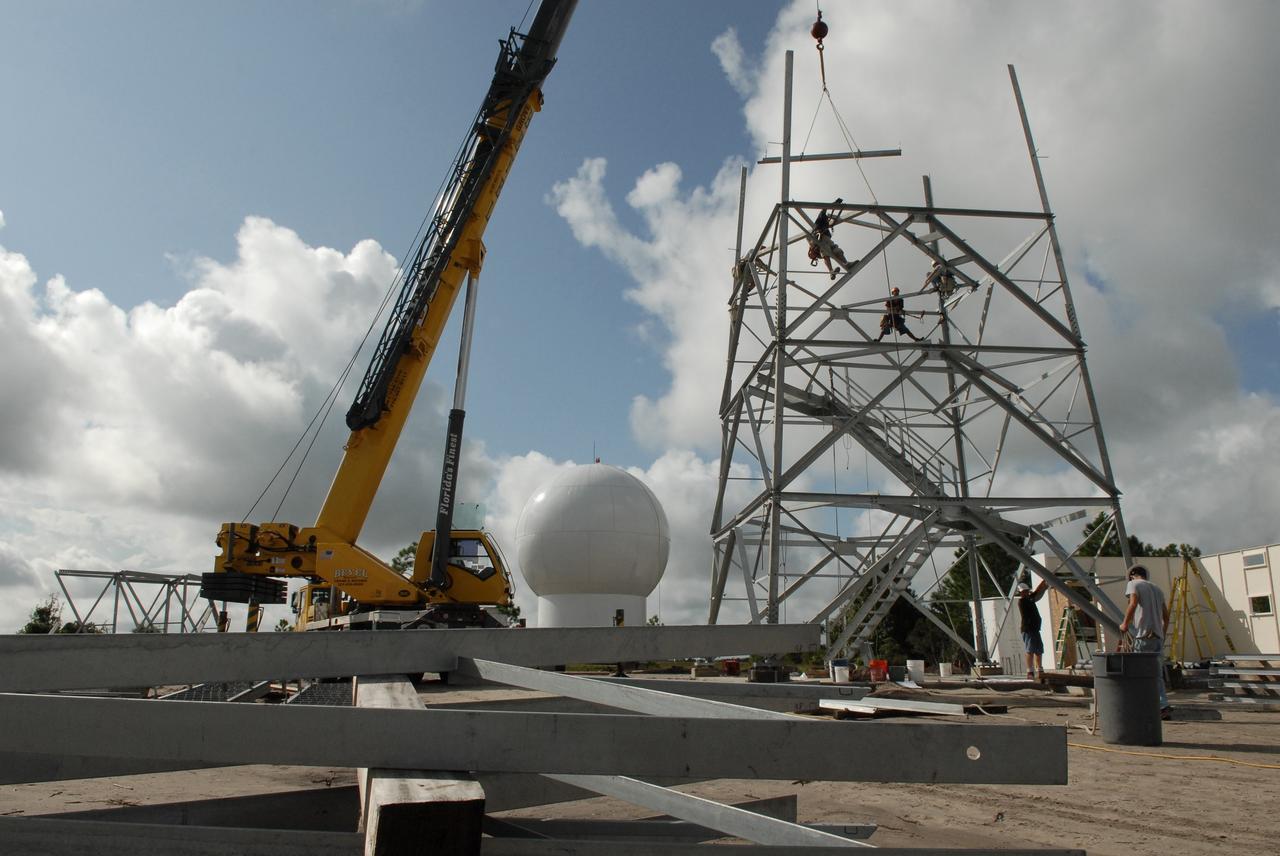 CAPE CANAVERAL, Fla. – In an area near S.R. 520 in Orange County, Florida, a crane lifts a steel beam that will be added to the being constructed for a Doppler weather radar facility for the 45th Weather Squadron. In the background is the radome that will be on top of the tower.  The new site replaces one at Patrick Air Force Base. It will be used by NASA's Kennedy Space Center, the 45th Space Wing and their customers. The site will be able to monitor weather conditions directly above and surrounding the launch pads at Kennedy.  The weather radar is essential in issuing lightning and other severe weather warnings and vital in evaluating lightning launch commit criteria.  The new radar, replacing what was installed 25 years ago at Patrick Air Force Base, includes Doppler capability to detect winds and identify the type, size and number of precipitation particles.  The site is ideally distant from the launch pads and has unobstructed views of Cape Canaveral Air Force Station and Kennedy. The radar will be used by forecasters at the USAF 45th Weather Squadron. Photo credit: NASA/Troy Cryder