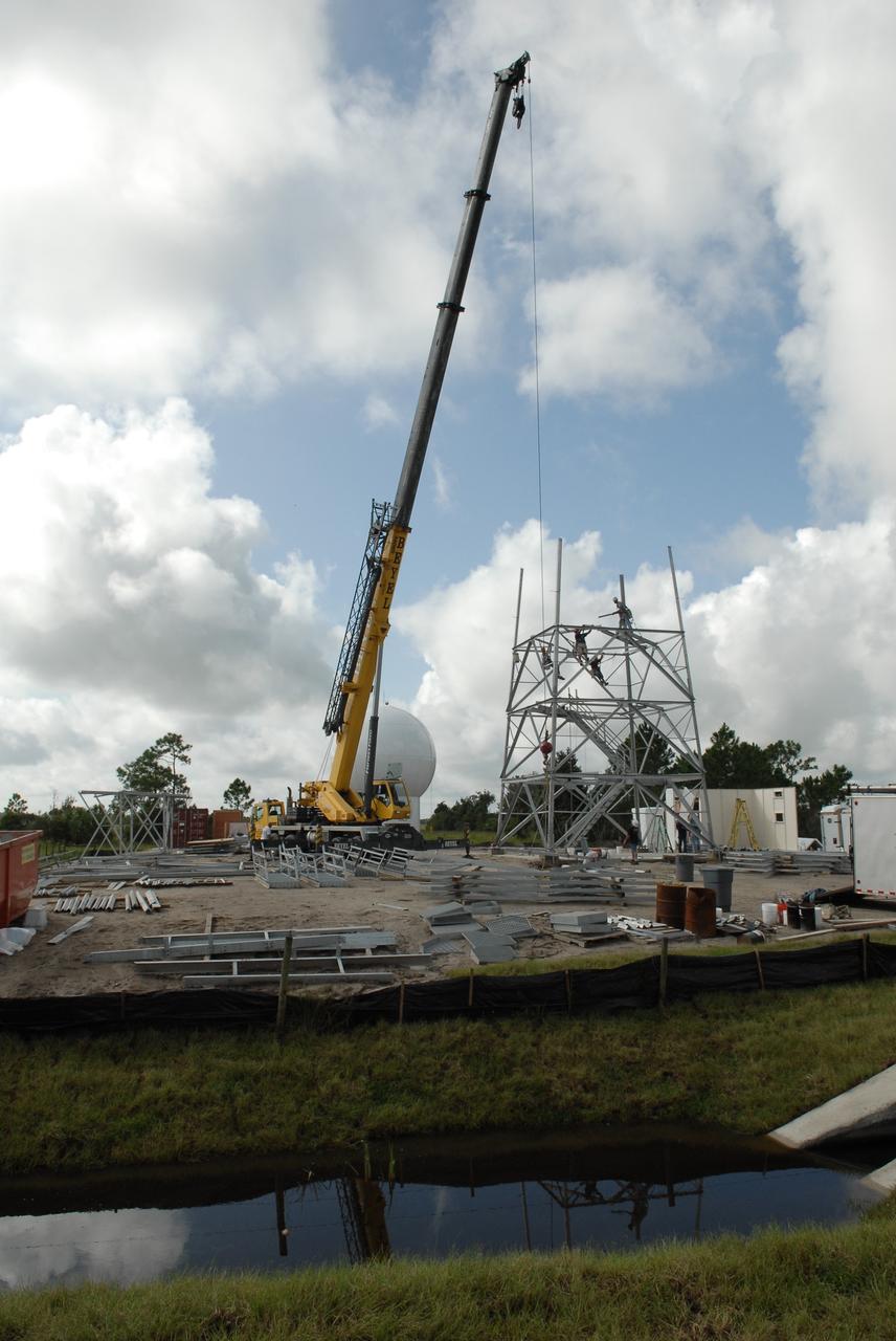 CAPE CANAVERAL, Fla. –  In an area near S.R. 520 in Orange County, Florida, a crane lifts a steel beam that will be added to the being constructed for a Doppler weather radar facility for the 45th Weather Squadron. In the background is the radome that will be on top of the tower.  The new site replaces one at Patrick Air Force Base. It will be used by NASA's Kennedy Space Center, the 45th Space Wing and their customers. The site will be able to monitor weather conditions directly above and surrounding the launch pads at Kennedy.  The weather radar is essential in issuing lightning and other severe weather warnings and vital in evaluating lightning launch commit criteria.  The new radar, replacing what was installed 25 years ago at Patrick Air Force Base, includes Doppler capability to detect winds and identify the type, size and number of precipitation particles.  The site is ideally distant from the launch pads and has unobstructed views of Cape Canaveral Air Force Station and Kennedy. The radar will be used by forecasters at the USAF 45th Weather Squadron. Photo credit: NASA/Troy Cryder