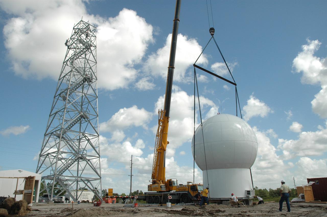 CAPE CANAVERAL, Fla. – In an area near S.R. 520 in Orange County, Florida, workers help guide the cables on a crane lifting a radome onto concrete blocks.  The radome will be lifted onto a steel tower constructed for a Doppler weather radar for the 45th Weather Squadron. The new site replaces one at Patrick Air Force Base and will be used by NASA's Kennedy Space Center, the U.S. Air Force's 45th Space Wing and their customers. The facility will be able to monitor weather conditions directly above and surrounding the launch pads at Kennedy.  The weather radar is essential in issuing lightning and other severe weather warnings and vital in evaluating lightning launch commit criteria.  Replacing what was installed 25 years ago at Patrick Air Force Base, the new radar includes Doppler capability to detect winds and identify the type, size and number of precipitation particles.  The site is ideally distant from the launch pads and has unobstructed views of Cape Canaveral Air Force Station and Kennedy. The radar will be used by forecasters at the USAF 45th Weather Squadron.  Photo credit: NASA/Jim Grossmann