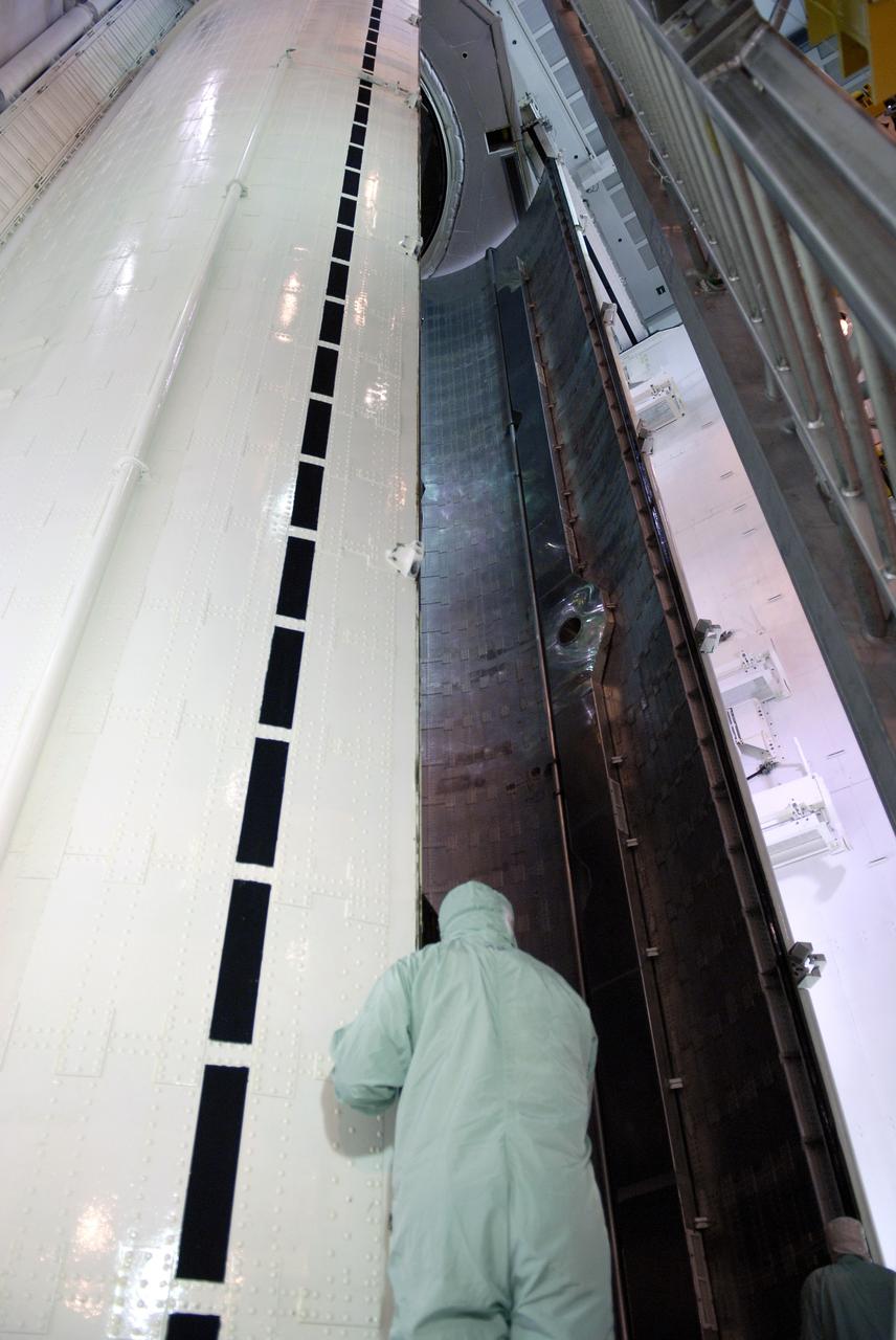 CAPE CANAVERAL, Fla. –    On Launch Pad 39A on NASA's Kennedy Space Center in Florida, a worker oversees the closing of the doors on the payload canister.  Space shuttle Atlantis’ HST payload for the STS-125 mission was moved from the shuttle into the canister.   The payload comprises four carriers holding various equipment for the mission.  The hardware will be transported back to Kennedy’s Payload Hazardous Servicing Facility where it will be stored until a new target launch date can be set for Atlantis’ STS-125 mission in 2009.  Atlantis’ October target launch date was delayed after a device on board Hubble used in the storage and transmission of science data to Earth shut down on Sept. 27.  Replacing the broken device will be added to Atlantis’ servicing mission to the telescope.  Photo credit: NASA/Kim Shiflett