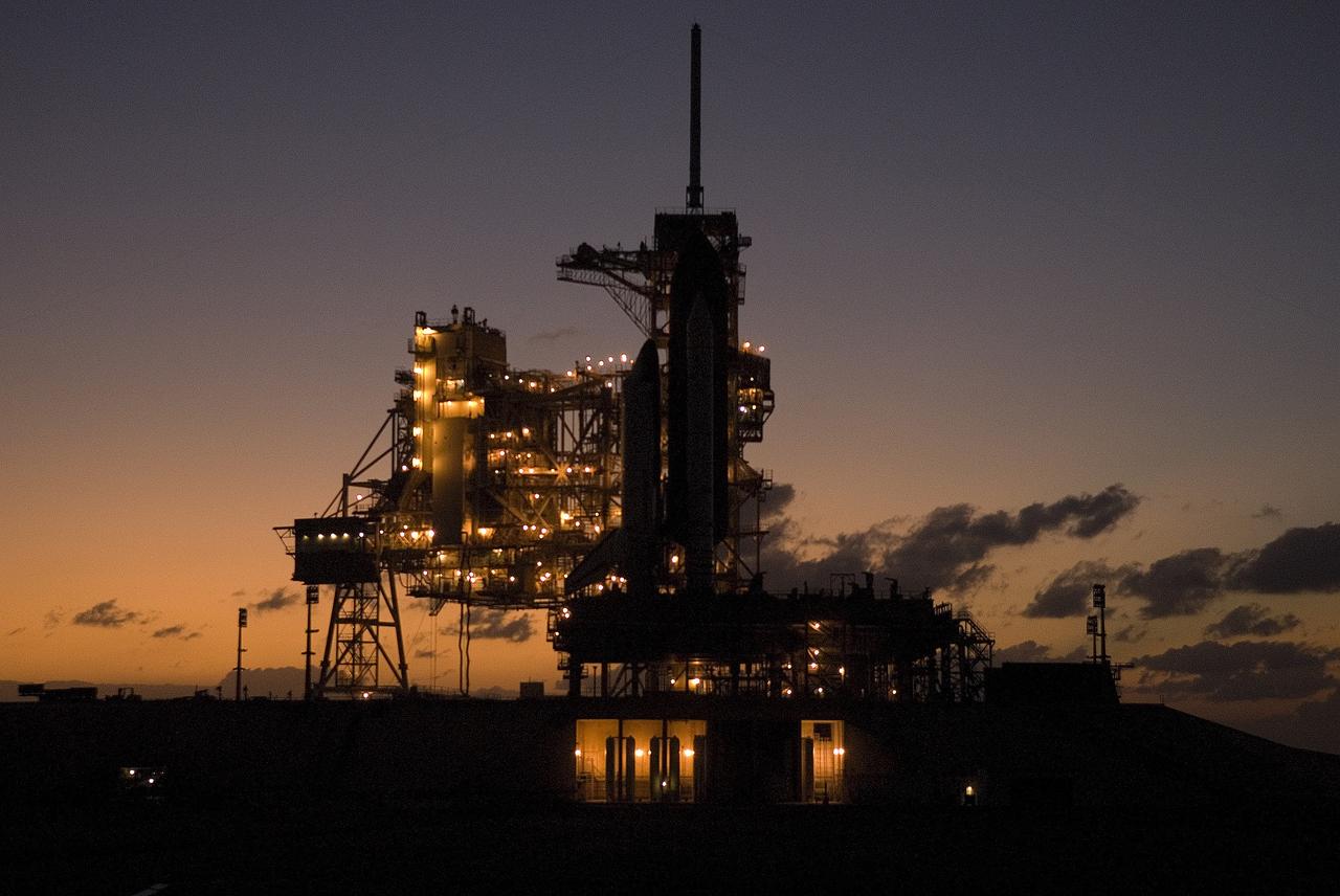 CAPE CANAVERAL, Fla. – As the sunset faces behind Launch Pad 39A at NASA's Kennedy Space Center in Florida, lights on the rotating and fixed service structures take over the luminescence in the night. Space shuttle Atlantis is on the pad. Atlantis’ October target launch date for the STS-125 Hubble Space Telescope servicing mission was delayed after a device on board Hubble used in the storage and transmission of science data to Earth shut down on Sept. 27. Replacing the broken device will be added to Atlantis’ servicing mission to the telescope. In the interim, Atlantis will be rolled back to the Vehicle Assembly Building until a new target launch date can be set for the mission in 2009. Photo credit: NASA/Troy Cryder