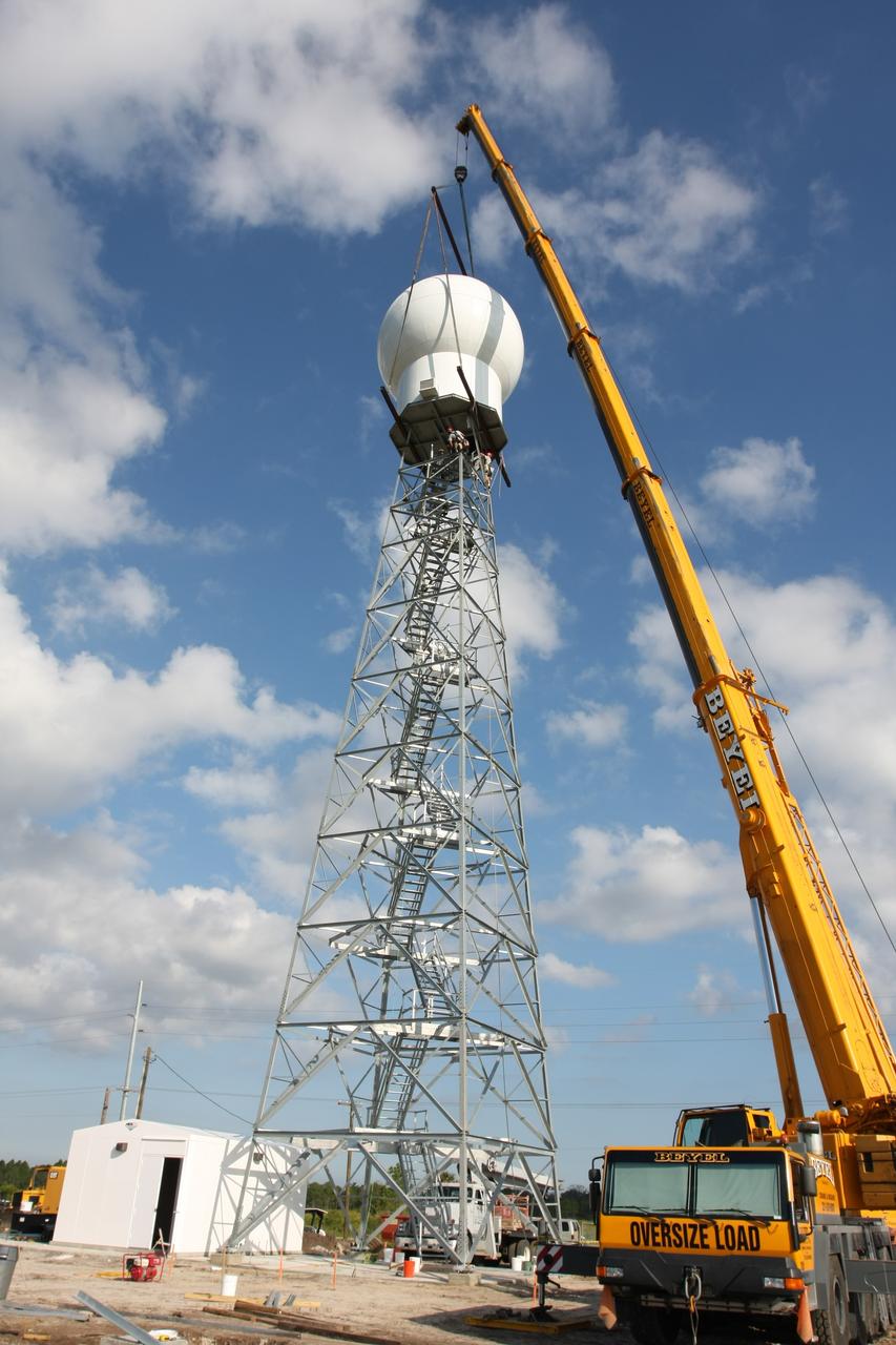 CAPE CANAVERAL, Fla. - A crane positions the radome on top of a new Doppler weather radar tower being built in an area near S.R. 520 in Orange County, Fla. The dome houses the weather radar dish and pedestal and protects them from the elements.  The new tower will replace one at nearby Patrick Air Force Base and will be used by NASA's Kennedy Space Center, the 45th Space Wing and their customers. The tower will be able to monitor weather conditions directly above the launch pads at Kennedy. The weather radar is essential in issuing lightning and other severe weather warnings and vital in evaluating lightning launch commit criteria. The new radar, replacing what was installed 25 years ago, includes Doppler capability to detect winds and identify the type, size and number of precipitation particles. The site is ideally distant from the launch pads and has unobstructed views of Cape Canaveral Air Force Station and Kennedy. Photo credit: NASA/Dimitri Gerondidakis