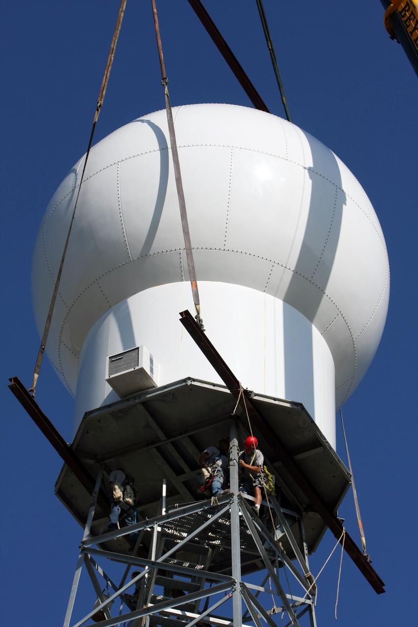 CAPE CANAVERAL, Fla. - Workers install the radome onto the top of a new Doppler weather radar tower being built in an area near S.R. 520 in Orange County, Fla. The dome houses the weather radar dish and pedestal and protects them from the elements.  The new tower will replace one at nearby Patrick Air Force Base and will be used by NASA's Kennedy Space Center, the 45th Space Wing and their customers. The tower will be able to monitor weather conditions directly above the launch pads at Kennedy. The weather radar is essential in issuing lightning and other severe weather warnings and vital in evaluating lightning launch commit criteria. The new radar, replacing what was installed 25 years ago, includes Doppler capability to detect winds and identify the type, size and number of precipitation particles. The site is ideally distant from the launch pads and has unobstructed views of Cape Canaveral Air Force Station and Kennedy. Photo credit: NASA/Dimitri Gerondidakis