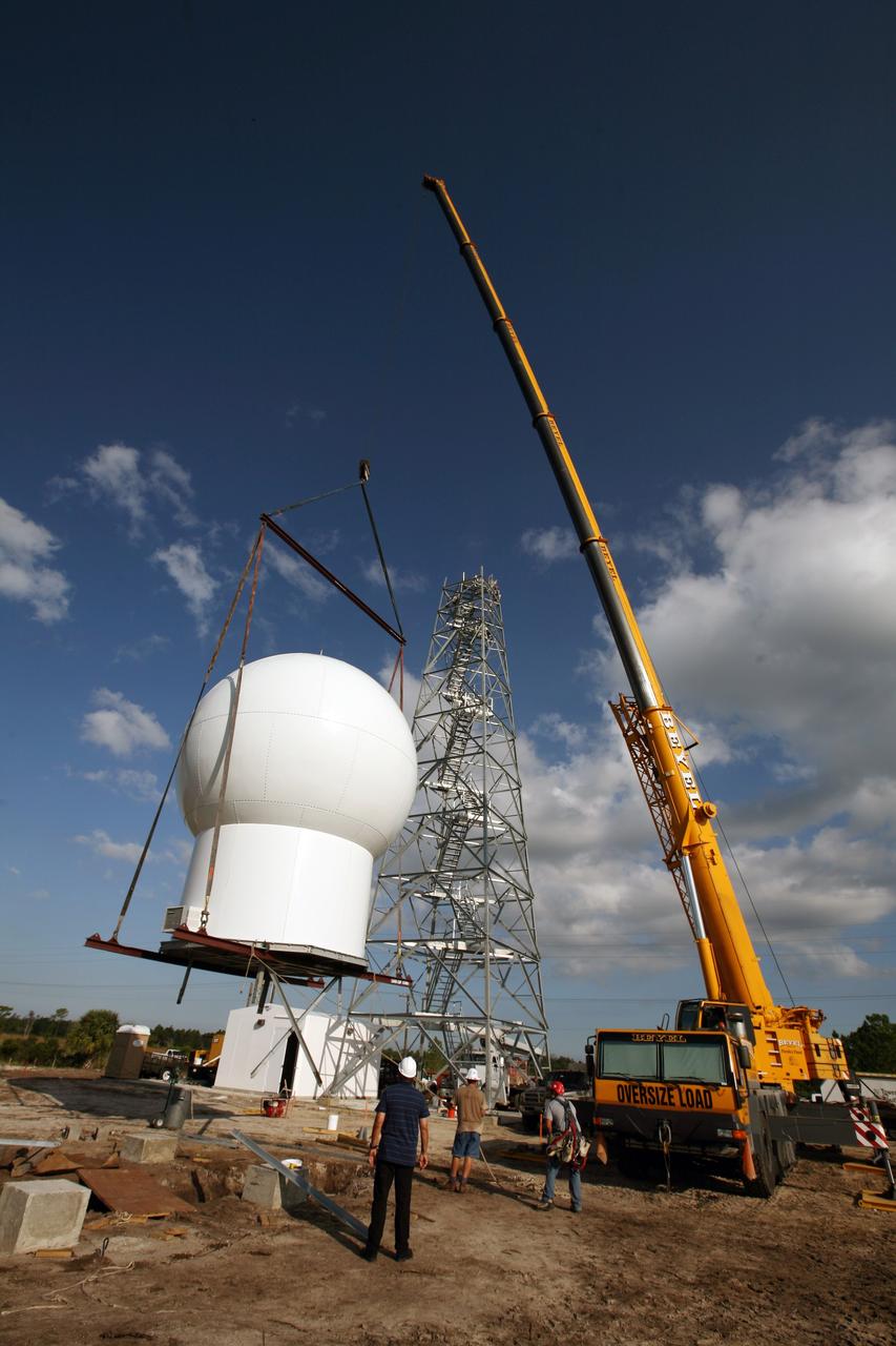CAPE CANAVERAL, Fla. - Joe Buchanan (left), project lead with the ITT Corporation for the 45th Space Wing, supervises the lift of the radome to the top of a new Doppler weather radar tower being built in an area near S.R. 520 in Orange County, Fla. The dome houses the weather radar dish and pedestal and protects them from the elements.  The new tower will replace one at nearby Patrick Air Force Base and will be used by NASA's Kennedy Space Center, the 45th Space Wing and their customers. The tower will be able to monitor weather conditions directly above the launch pads at Kennedy. The weather radar is essential in issuing lightning and other severe weather warnings and vital in evaluating lightning launch commit criteria. The new radar, replacing what was installed 25 years ago, includes Doppler capability to detect winds and identify the type, size and number of precipitation particles. The site is ideally distant from the launch pads and has unobstructed views of Cape Canaveral Air Force Station and Kennedy. Photo credit: NASA/Dimitri Gerondidakis