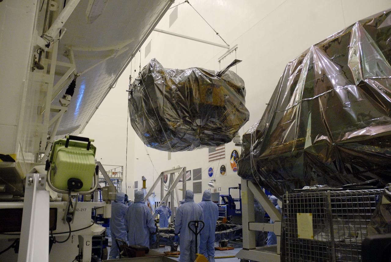 CAPE CANAVERAL, Fla. - In the Payload Hazardous Servicing Facility, or PHSF, at NASA's Kennedy Space Center in Florida, workers watch as the Orbital Replacement Unit Carrier, or ORUC, is lowered from the payload canister which transported the Hubble Space Telescope equipment back to the clean room from Launch Pad 39A.  In the foreground is the Super Lightweight Interchangeable Carrier, or SLIC.  The payload for Hubble servicing mission 4 comprises four carriers holding various equipment for the mission. In the PHSF, the carriers will be stored until a new target launch date in 2009 can be set for Atlantis’ STS-125 mission. Atlantis’ October target launch date was delayed after a device on board Hubble, used in the storage and transmission of science data to Earth, shut down on Sept. 27. Replacing the broken device will be added to Atlantis’ servicing mission to the telescope.  Photo credit: NASA/Jim Grossmann