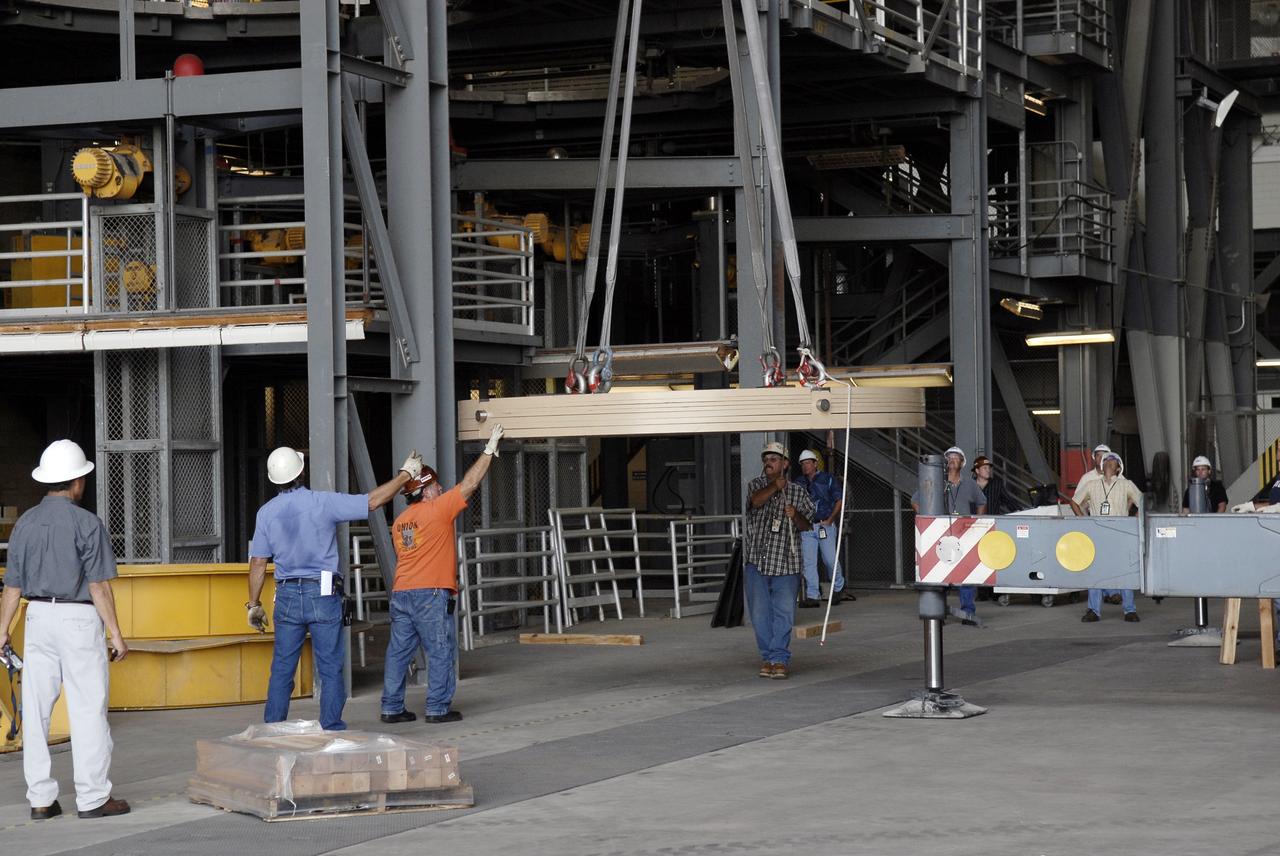 CAPE CANAVERAL, Fla. - Workers lift the Ares IX upper stage segments’ ballast assemblies off a truck in high bay 4 of the Vehicle Assembly Building at NASA’s Kennedy Space Center, part of the preparations for the test of the Ares IX rocket. These ballast assemblies will be installed in the upper stage 1 and 7 segments and will mimic the mass of the fuel.  Their total weight is approximately 160,000 pounds.  The test launch of the Ares IX in 2009 will be the first designed to determine the flight-worthiness of the Ares I rocket.  Ares I is an in-line, two-stage rocket that will transport the Orion crew exploration vehicle to low-Earth orbit. The Ares I first stage will be a five-segment solid rocket booster based on the four-segment design used for the space shuttle. Ares I’s fifth booster segment allows the launch vehicle to lift more weight and reach a higher altitude before the first stage separates from the upper stage, which ignites in midflight to propel the Orion spacecraft to Earth orbit.  Photo credit: NASA/Kim Shiflett