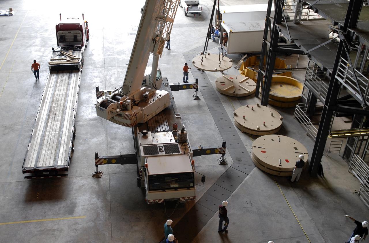CAPE CANAVERAL, Fla. - Workers position Ares IX upper stage segments’ ballast assemblies along the floor of high bay 4 in the Vehicle Assembly Building at NASA’s Kennedy Space Center, part of the preparations for the test of the Ares IX rocket. These ballast assemblies will be installed in the upper stage 1 and 7 segments and will mimic the mass of the fuel.  Their total weight is approximately 160,000 pounds.  The test launch of the Ares IX in 2009 will be the first designed to determine the flight-worthiness of the Ares I rocket.  Ares I is an in-line, two-stage rocket that will transport the Orion crew exploration vehicle to low-Earth orbit. The Ares I first stage will be a five-segment solid rocket booster based on the four-segment design used for the space shuttle. Ares I’s fifth booster segment allows the launch vehicle to lift more weight and reach a higher altitude before the first stage separates from the upper stage, which ignites in midflight to propel the Orion spacecraft to Earth orbit.  Photo credit: NASA/Kim Shiflett