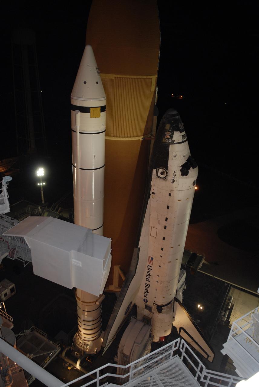 CAPE CANAVERAL, Fla. - Space Shuttle Atlantis is viewed from an upper level of the fixed service structure on Launch Pad 39A at NASA's Kennedy Space Center in Florida.  Visible are the orange external tank, a solid rocket booster and Atlantis.  In the foreground is the White Room at the end of the orbiter access arm. Atlantis is rolling back to the Vehicle Assembly Building to await launch on its STS-125 mission to repair NASA's Hubble Space Telescope.  Atlantis' targeted launch on Oct. 14 was delayed when a system that transfers science data from the orbiting observatory to Earth malfunctioned on Sept. 27. The new target launch date is under review.  The space shuttle is mounted on a Mobile Launcher Platform and will be delivered to the Vehicle Assembly Building atop a crawler transporter. traveling slower than 1 mph during the 3.4-mile journey.  The rollback is expected to take approximately six hours.  Photo credit: NASA/Kim Shiflett