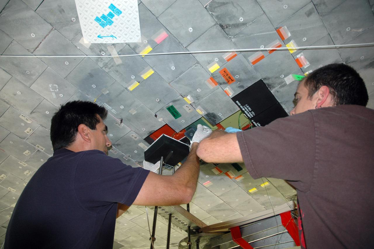 CAPE CANAVERAL, Fla. - In Orbiter Processing Facility bay 3 at NASA's Kennedy Space Center in Florida, workers attach boundary layer transition, or BLT, tile to space shuttle Discovery before its launch on the STS-119 mission in February 2009. The specially modified tiles and instrumentation package will monitor the heating effects of early re-entry boundary layer transition at high mach numbers. These data support analytical modeling and design efforts for both the space shuttles and NASA next-generation spacecraft, the Orion crew exploration vehicle. On the STS-119 mission, Discovery also will carry the S6 truss segment to complete the 361-foot-long backbone of the International Space Station. The truss includes the fourth pair of solar array wings and electronics that convert sunlight to power for the orbiting laboratory. Photo credit: NASA/Tim Jacobs