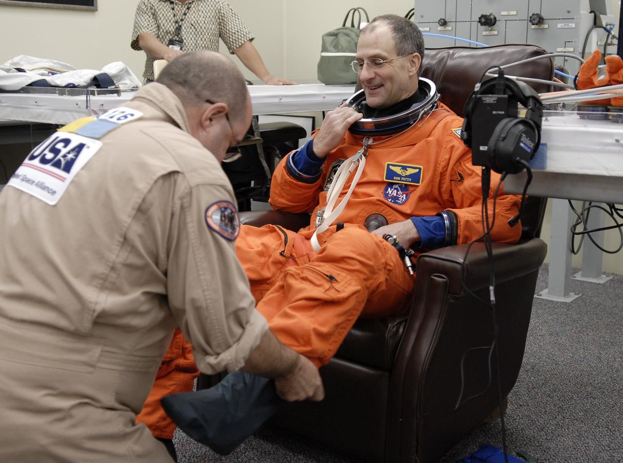 CAPE CANAVERAL, Fla. –  STS-126 Mission Specialist Donald Pettit is helped by a suit technician with his boots during suit-up in the Operations and Checkout Building at NASA's Kennedy Space Center in Florida. Pettit and other crew members are having their launch-and-entry suits fit-checked prior to heading for Launch Pad 39A. The crew will take part in a simulated launch countdown at the pad. The crew is at Kennedy to take part in the Terminal Countdown Demonstration Test, which includes equipment familiarization, emergency exit training and the simulated countdown.  On the STS-126 mission, space shuttle Endeavour's crew will deliver equipment and supplies to the International Space Station in preparation for expansion from a three- to six-person resident crew aboard the complex. The mission also will include four spacewalks to service the station’s Solar Alpha Rotary Joints. Endeavour is targeted to launch Nov. 14. Photo credit: NASA/Kim Shiflett