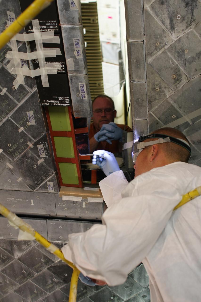 CAPE CANAVERAL, Fla. – United Space Alliance technicians remove and replace all the hub tiles on space shuttle Discovery before its STS-119 mission targeted for Feb. 12. Hub tiles, heat protection tiles, are difficult to install because of their location on the inboard side of the inboard elevons. On the STS-119 mission, Discovery will carry the S6 truss segment to complete the 361-foot-long backbone of the International Space Station. The truss includes the fourth pair of solar array wings and electronics that convert sunlight to power for the orbiting laboratory. Photo credit: NASA/Dimitri Gerondidakis