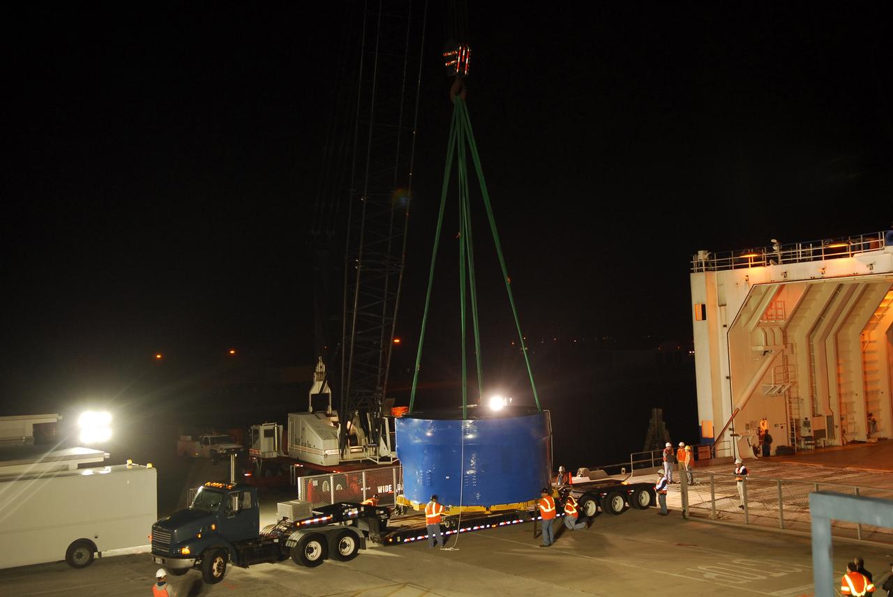 CAPE CANAVERAL, Fla. – A crane lifts and transfers an Ares I-X upper stage simulator segment from the Delta Mariner at Port Canaveral, Fla., onto a flatbed truck. They will be transported to the Vehicle Assembly Building's high bay 4 at NASA's Kennedy Space Center in Florida. The upper stage simulator will be used in the test flight identified as Ares I-X in 2009. The Ares I-X test flight will provide NASA an early opportunity to test and prove hardware, facilities and ground operations associated with the Ares I crew launch vehicle. It also will allow NASA to gather critical data during ascent of the integrated Orion crew exploration vehicle and the Ares I rocket. The data will ensure the entire vehicle system is safe and fully operational before astronauts begin traveling to orbit. The simulator segments will simulate the mass and the outer mold line and will be more than 100 feet of the total vehicle height of 327 feet. The simulator comprises 11 segments that are approximately 18 feet in diameter. Most of the segments will be approximately 10 feet high, ranging in weight from 18,000 to 60,000 pounds, for a total of approximately 450,000 pounds. Photo credit: NASA/Cory Huston