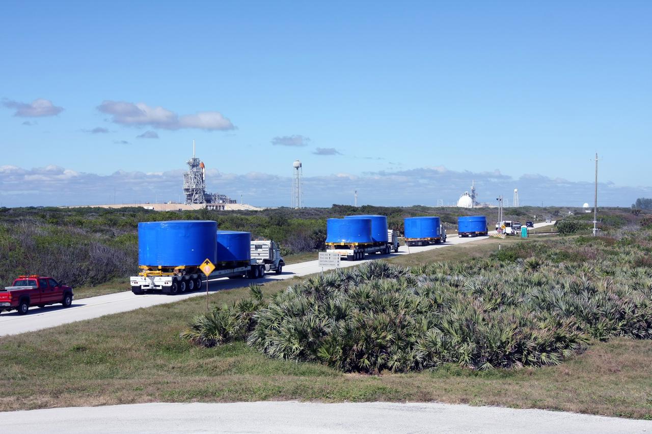 CAPE CANAVERAL, Fla. – A convoy of trucks passes a launch pad as it makes the journey from Port Canaveral, Fla., to the Vehicle Assembly Building's high bay 4 at NASA's Kennedy Space Center in Florida. The trucks carry Ares I-X upper stage simulator segments. The upper stage simulators will be used in the test flight identified as Ares I-X in 2009. The Ares I-X test flight will provide NASA an early opportunity to test and prove hardware, facilities and ground operations associated with the Ares I crew launch vehicle. It also will allow NASA to gather critical data during ascent of the integrated Orion crew exploration vehicle and the Ares I rocket. The data will ensure the entire vehicle system is safe and fully operational before astronauts begin traveling to orbit. The simulator segments will simulate the mass and the outer mold line and will be more than 100 feet of the total vehicle height of 327 feet. The simulator comprises 11 segments that are approximately 18 feet in diameter. Most of the segments will be approximately 10 feet high, ranging in weight from 18,000 to 60,000 pounds, for a total of approximately 450,000 pounds. Photo credit: NASA/Cory Huston