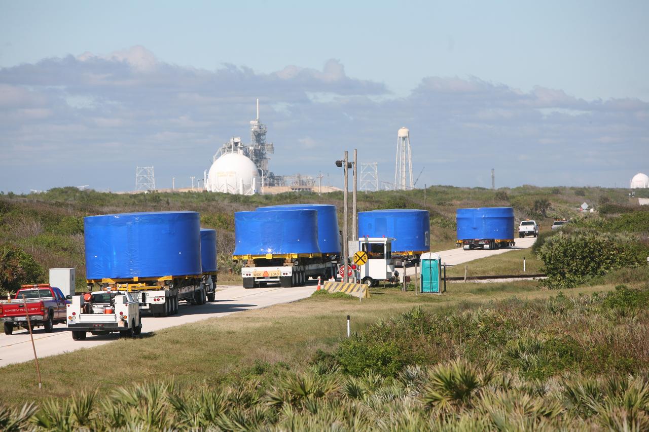 CAPE CANAVERAL, Fla. – A convoy of trucks passes a launch pad as it makes the journey from Port Canaveral, Fla., to the Vehicle Assembly Building's high bay 4 at NASA's Kennedy Space Center in Florida. The trucks carry Ares I-X upper stage simulator segments. The upper stage simulators will be used in the test flight identified as Ares I-X in 2009. The Ares I-X test flight will provide NASA an early opportunity to test and prove hardware, facilities and ground operations associated with the Ares I crew launch vehicle. It also will allow NASA to gather critical data during ascent of the integrated Orion crew exploration vehicle and the Ares I rocket. The data will ensure the entire vehicle system is safe and fully operational before astronauts begin traveling to orbit. The simulator segments will simulate the mass and the outer mold line and will be more than 100 feet of the total vehicle height of 327 feet. The simulator comprises 11 segments that are approximately 18 feet in diameter. Most of the segments will be approximately 10 feet high, ranging in weight from 18,000 to 60,000 pounds, for a total of approximately 450,000 pounds. Photo credit: NASA/Cory Huston
