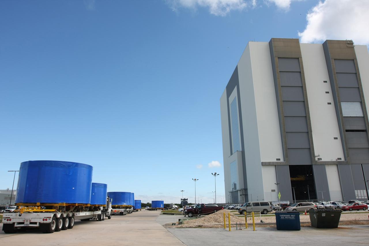 CAPE CANAVERAL, Fla. – A convoy of trucks arrives at the Vehicle Assembly Building's high bay 4 at NASA's Kennedy Space Center in Florida. The trucks carry Ares I-X upper stage simulator segments which arrived at Port Canaveral, Fla., Nov. 4. The upper stage simulators will be used in the test flight identified as Ares I-X in 2009. The Ares I-X test flight will provide NASA an early opportunity to test and prove hardware, facilities and ground operations associated with the Ares I crew launch vehicle. It also will allow NASA to gather critical data during ascent of the integrated Orion crew exploration vehicle and the Ares I rocket. The data will ensure the entire vehicle system is safe and fully operational before astronauts begin traveling to orbit. The simulator segments will simulate the mass and the outer mold line and will be more than 100 feet of the total vehicle height of 327 feet. The simulator comprises 11 segments that are approximately 18 feet in diameter. Most of the segments will be approximately 10 feet high, ranging in weight from 18,000 to 60,000 pounds, for a total of approximately 450,000 pounds. Photo credit: NASA/Cory Huston