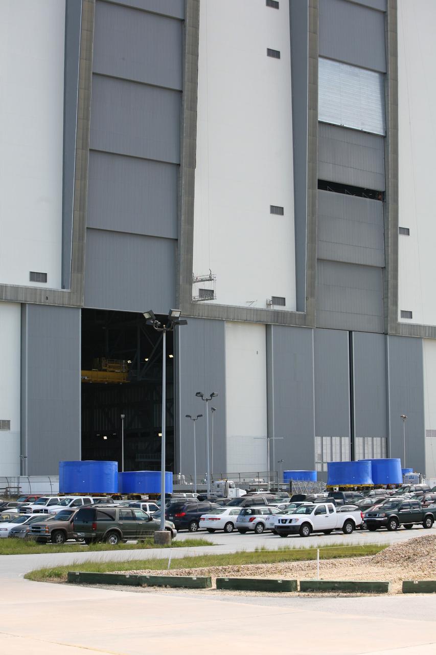 CAPE CANAVERAL, Fla. – Trucks carrying the blue Ares I-X upper stage simulator segments are lined up outside the Vehicle Assembly Building's high bay 4 at NASA's Kennedy Space Center in Florida. The segments will be offloaded inside bay 4. The upper stage simulators will be used in the test flight identified as Ares I-X in 2009. The Ares I-X test flight will provide NASA an early opportunity to test and prove hardware, facilities and ground operations associated with the Ares I crew launch vehicle. It also will allow NASA to gather critical data during ascent of the integrated Orion crew exploration vehicle and the Ares I rocket. The data will ensure the entire vehicle system is safe and fully operational before astronauts begin traveling to orbit. The simulator segments will simulate the mass and the outer mold line and will be more than 100 feet of the total vehicle height of 327 feet. The simulator comprises 11 segments that are approximately 18 feet in diameter. Most of the segments will be approximately 10 feet high, ranging in weight from 18,000 to 60,000 pounds, for a total of approximately 450,000 pounds. Photo credit: NASA/Cory Huston