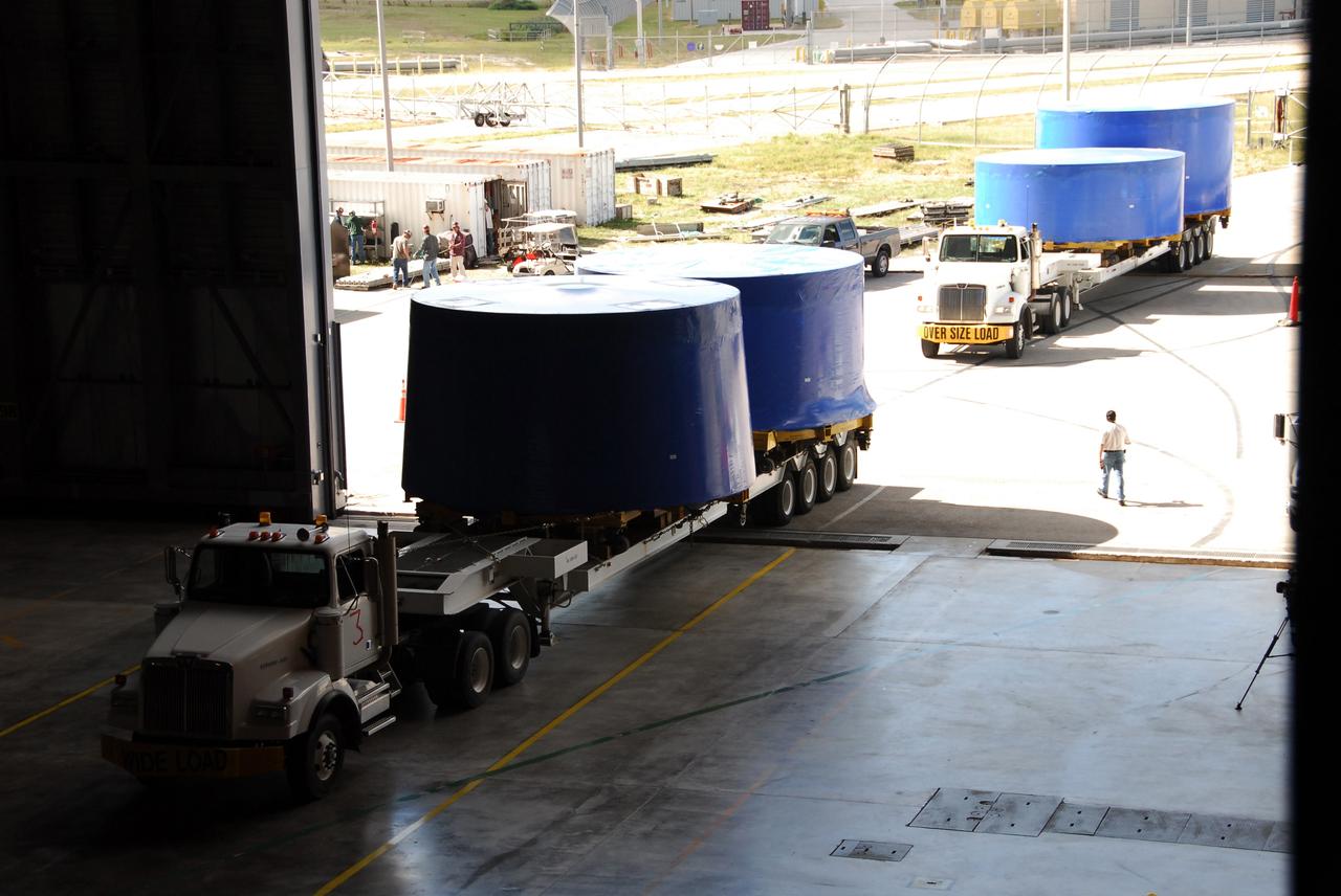 CAPE CANAVERAL, Fla. – Trucks pull into the Vehicle Assembly Building's high bay 4 at NASA's Kennedy Space Center in Florida. They carry Ares I-X upper stage simulator segments that arrived Nov. 4 at Port Canaveral, Fla., aboard the Delta Mariner. The upper stage simulators will be used in the test flight identified as Ares I-X in 2009. The Ares I-X test flight will provide NASA an early opportunity to test and prove hardware, facilities and ground operations associated with the Ares I crew launch vehicle. It also will allow NASA to gather critical data during ascent of the integrated Orion crew exploration vehicle and the Ares I rocket. The data will ensure the entire vehicle system is safe and fully operational before astronauts begin traveling to orbit. The simulator segments will simulate the mass and the outer mold line and will be more than 100 feet of the total vehicle height of 327 feet. The simulator comprises 11 segments that are approximately 18 feet in diameter. Most of the segments will be approximately 10 feet high, ranging in weight from 18,000 to 60,000 pounds, for a total of approximately 450,000 pounds. Photo credit: NASA/Cory Huston