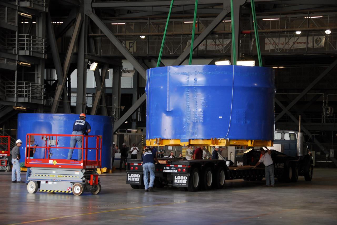 CAPE CANAVERAL, Fla. – Inside the Vehicle Assembly Building's high bay 4 at NASA's Kennedy Space Center in Florida, workers secure the crane that will lift one of the Ares I-X upper stage simulator segments from its transporter. The segments, which arrived Nov. 4 at Port Canaveral, Fla., aboard the Delta Mariner, will be placed on the floor. The upper simulator segments are moved inside where they will be offloaded. The upper stage simulators will be used in the test flight identified as Ares I-X in 2009. The Ares I-X test flight will provide NASA an early opportunity to test and prove hardware, facilities and ground operations associated with the Ares I crew launch vehicle. It also will allow NASA to gather critical data during ascent of the integrated Orion crew exploration vehicle and the Ares I rocket. The data will ensure the entire vehicle system is safe and fully operational before astronauts begin traveling to orbit. The simulator segments will simulate the mass and the outer mold line and will be more than 100 feet of the total vehicle height of 327 feet. The simulator comprises 11 segments that are approximately 18 feet in diameter. Most of the segments will be approximately 10 feet high, ranging in weight from 18,000 to 60,000 pounds, for a total of approximately 450,000 pounds. Photo credit: NASA/Cory Huston