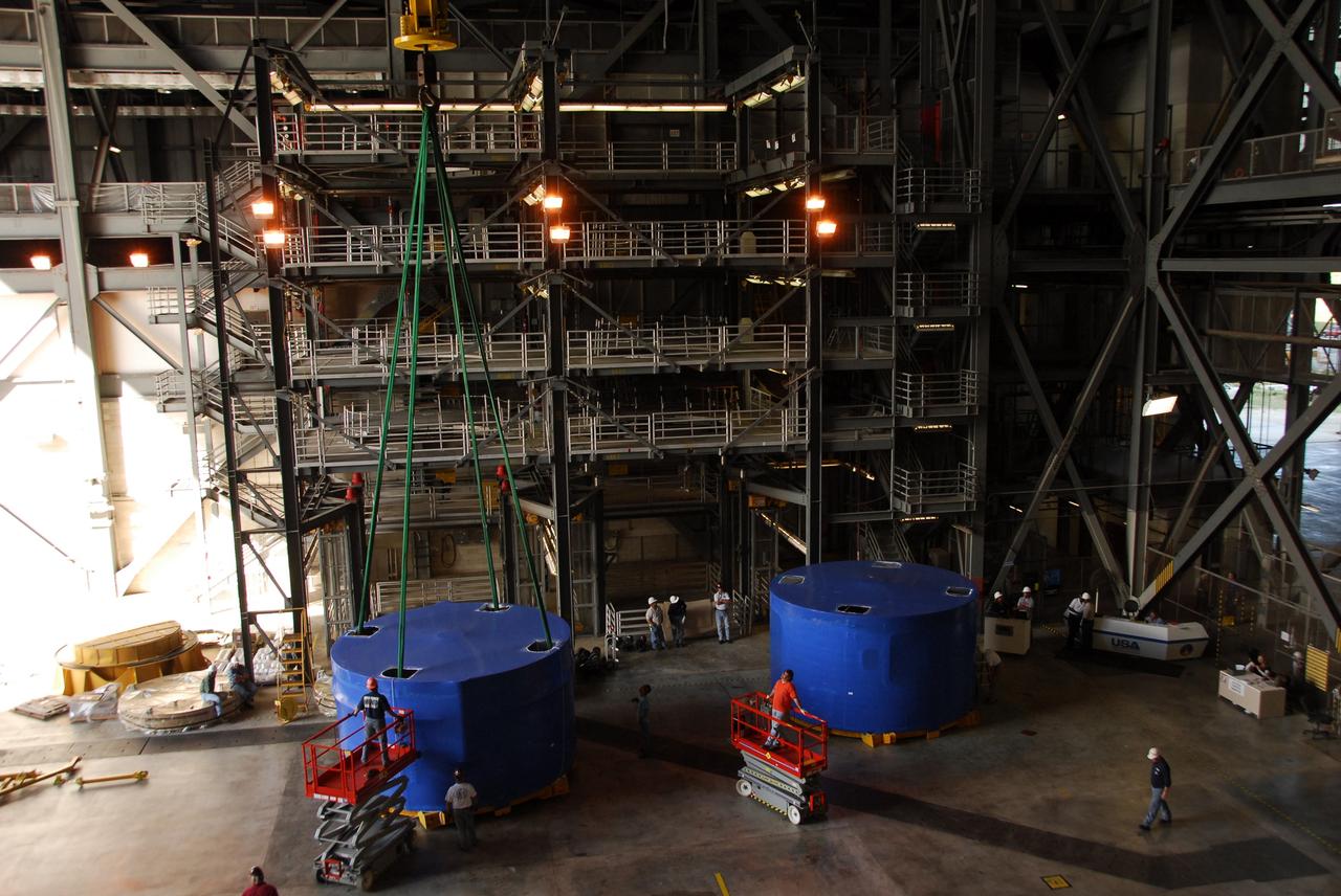 CAPE CANAVERAL, Fla. – Inside the Vehicle Assembly Building's high bay 4 at NASA's Kennedy Space Center in Florida, two of the Ares I-X upper stage simulator segments are offloaded from its transporter and placed on the floor. The segments arrived Nov. 4 at Port Canaveral, Fla., aboard the Delta Mariner. The upper stage simulators will be used in the test flight identified as Ares I-X in 2009. The Ares I-X test flight will provide NASA an early opportunity to test and prove hardware, facilities and ground operations associated with the Ares I crew launch vehicle. It also will allow NASA to gather critical data during ascent of the integrated Orion crew exploration vehicle and the Ares I rocket. The data will ensure the entire vehicle system is safe and fully operational before astronauts begin traveling to orbit. The simulator segments will simulate the mass and the outer mold line and will be more than 100 feet of the total vehicle height of 327 feet. The simulator comprises 11 segments that are approximately 18 feet in diameter. Most of the segments will be approximately 10 feet high, ranging in weight from 18,000 to 60,000 pounds, for a total of approximately 450,000 pounds. Photo credit: NASA/Cory Huston