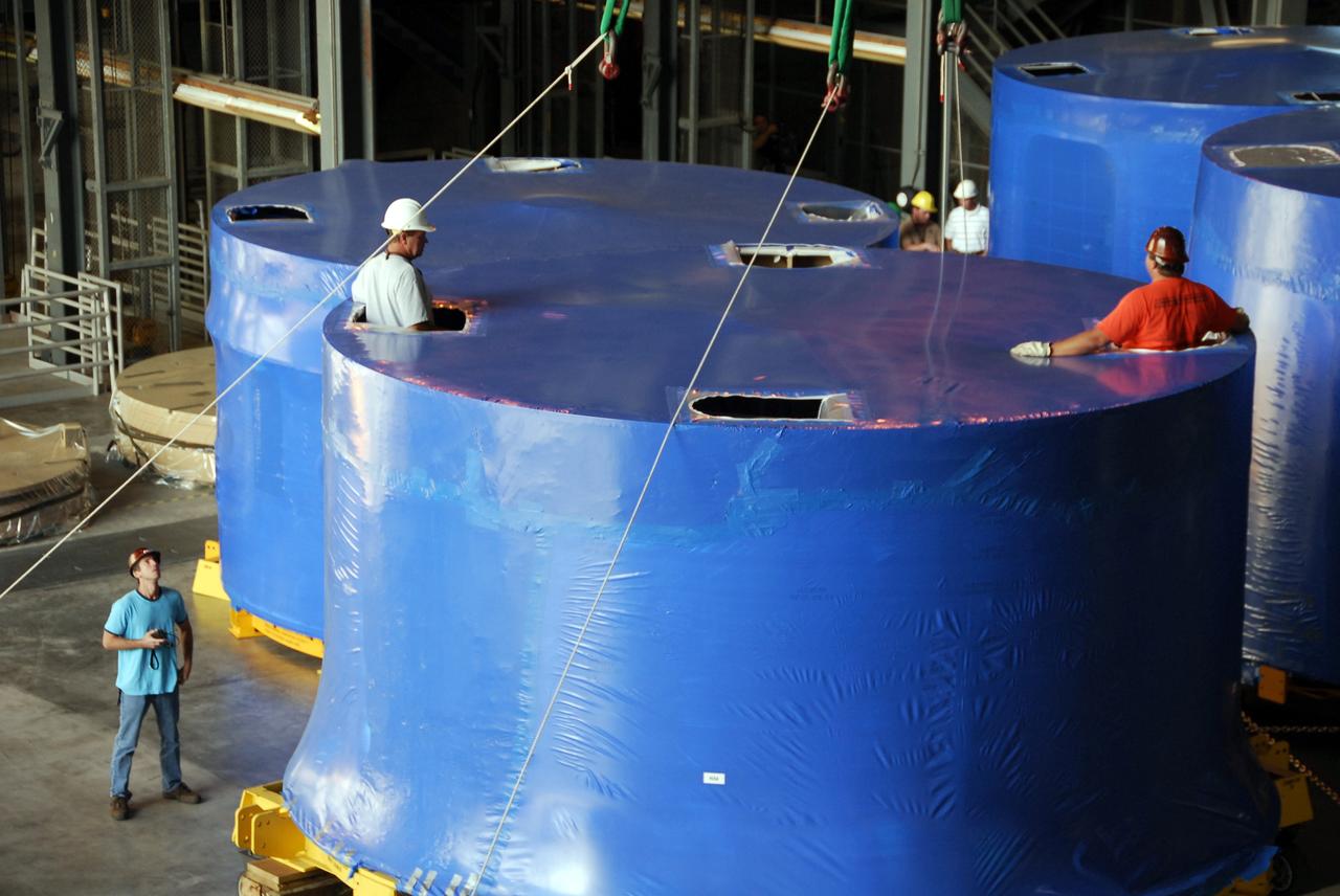CAPE CANAVERAL, Fla. – Inside the Vehicle Assembly Building's high bay 4 at NASA's Kennedy Space Center in Florida, workers secure the cranes that are being used to offload Ares I-X upper stage simulator segments onto the floor. The segments arrived Nov. 4 at Port Canaveral, Fla., aboard the Delta Mariner. The upper simulator segments are moved inside where they will be offloaded. The upper stage simulators will be used in the test flight identified as Ares I-X in 2009. The Ares I-X test flight will provide NASA an early opportunity to test and prove hardware, facilities and ground operations associated with the Ares I crew launch vehicle. It also will allow NASA to gather critical data during ascent of the integrated Orion crew exploration vehicle and the Ares I rocket. The data will ensure the entire vehicle system is safe and fully operational before astronauts begin traveling to orbit. The simulator segments will simulate the mass and the outer mold line and will be more than 100 feet of the total vehicle height of 327 feet. The simulator comprises 11 segments that are approximately 18 feet in diameter. Most of the segments will be approximately 10 feet high, ranging in weight from 18,000 to 60,000 pounds, for a total of approximately 450,000 pounds. Photo credit: NASA/Cory Huston