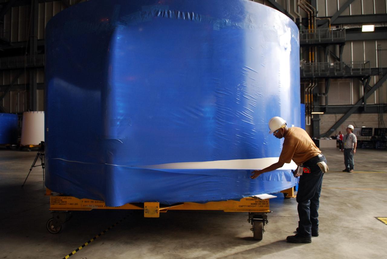 CAPE CANAVERAL, Fla. – Inside the Vehicle Assembly Building high bay 4 at NASA's Kennedy Space Center in Florida, workers from NASA's Glenn Research Center remove the blue shrink-wrapped covers on these Ares I-X upper stage simulator segments. The protective covers were used for shipping. The upper stage simulator will be used in the test flight identified as Ares I-X in 2009. The segments will simulate the mass and the outer mold line and will be more than 100 feet of the total vehicle height of 327 feet. The simulator comprises 11 segments that are approximately 18 feet in diameter. Most of the segments will be approximately 10 feet high, ranging in weight from 18,000 to 60,000 pounds, for a total of approximately 450,000 pounds. Photo credit: NASA/Troy Cryder