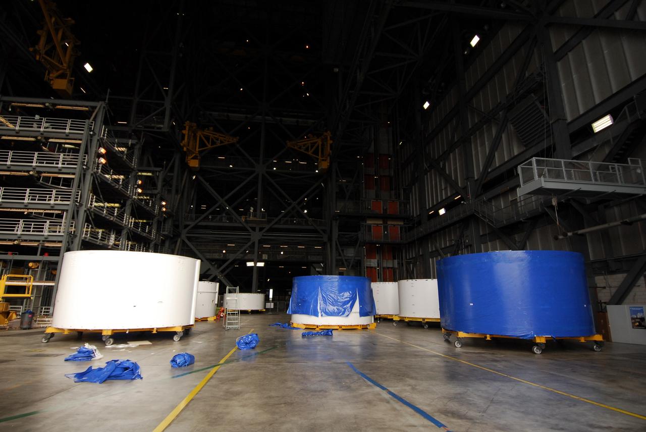 CAPE CANAVERAL, Fla. – Inside the Vehicle Assembly Building high bay 4 at NASA's Kennedy Space Center in Florida, Ares I-X upper stage simulator segments are lined up. Their protective blue shrink-wrapped covers used for shipping are being removed, as seen on the segments at left and in the back. The upper stage simulator will be used in the test flight identified as Ares I-X in 2009. The segments will simulate the mass and the outer mold line and will be more than 100 feet of the total vehicle height of 327 feet. The simulator comprises 11 segments that are approximately 18 feet in diameter. Most of the segments will be approximately 10 feet high, ranging in weight from 18,000 to 60,000 pounds, for a total of approximately 450,000 pounds. Photo credit: NASA/Troy Cryder