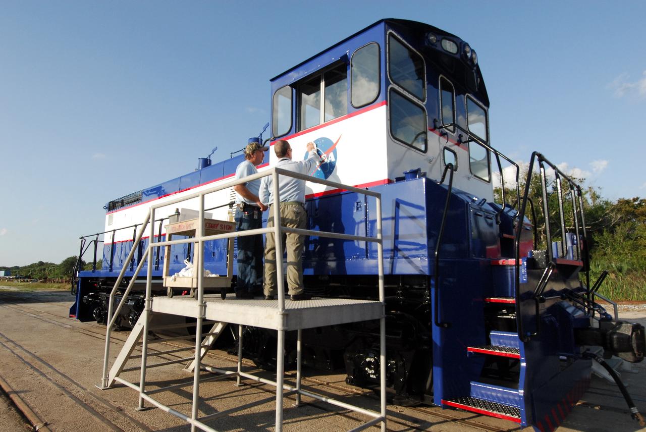 CAPE CANAVERAL, Fla. – At NASA's Kennedy Space Center in Florida, Ron Burrill (left) and Phil Moore place a new NASA insignia on the side of NASA Railroad locomotive 3. The Railroad Operation and Maintenance Team at Kennedy completed the refurbishment of locomotive 3 in October. The 15-month process, including a new paint scheme, dealt with extensive corrosion to the locomotive because of Kennedy's proximity to the Atlantic Ocean. Locomotives 1 and 2 also will be refurbished eventually. The NASA Railroad locomotives are SW-1500 switch engines built by Electro Motive Diesel (EMD). Photo credit: NASA/Amanda Diller
