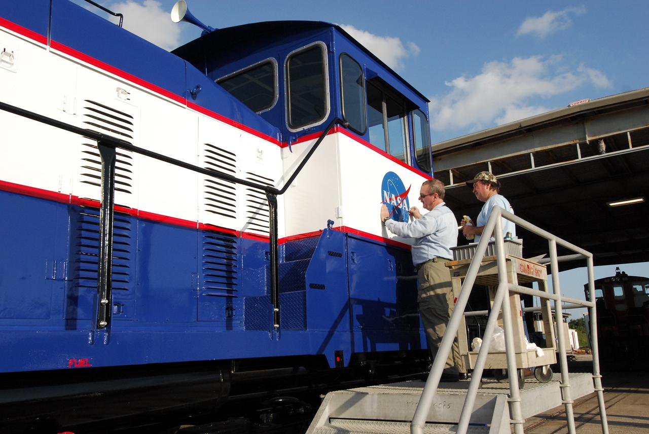 CAPE CANAVERAL, Fla. – At NASA's Kennedy Space Center in Florida, Phil Moore (left) and Ron Burrill place a new NASA insignia on the side of NASA Railroad locomotive 3. The Railroad Operation and Maintenance Team at Kennedy completed the refurbishment of locomotive 3 in October. The 15-month process, including a new paint scheme, dealt with extensive corrosion to the locomotive because of Kennedy's proximity to the Atlantic Ocean. Locomotives 1 and 2 also will be refurbished eventually. The NASA Railroad locomotives are SW-1500 switch engines built by Electro Motive Diesel (EMD). Photo credit: NASA/Amanda Diller