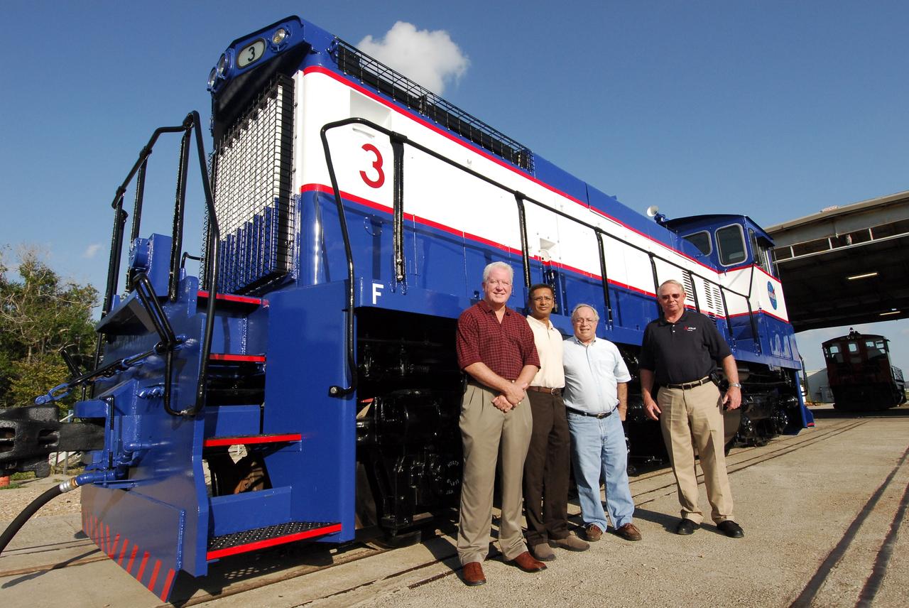 CAPE CANAVERAL, Fla. –   At NASA's Kennedy Space Center in Florida, the NASA Railroad and Transportation Management Team poses alongside NASA Railroad locomotive 3.  From left are John Muzzy, with EG&G, Sandeep Wilkhu, with NASA, and Tony Adrade and Chuck Sturgill, with EG&G.  The Railroad Operation and Maintenance Team at Kennedy completed the refurbishment of locomotive 3 in October.  The 15-month process, including a new paint scheme, dealt with extensive corrosion to the locomotive because of Kennedy's proximity to the Atlantic Ocean.  Locomotives 1 and 2 also will be refurbished eventually.  The NASA Railroad locomotives are SW-1500 switch engines built by Electro Motive Diesel (EMD).  Photo credit:  NASA/Amanda Diller