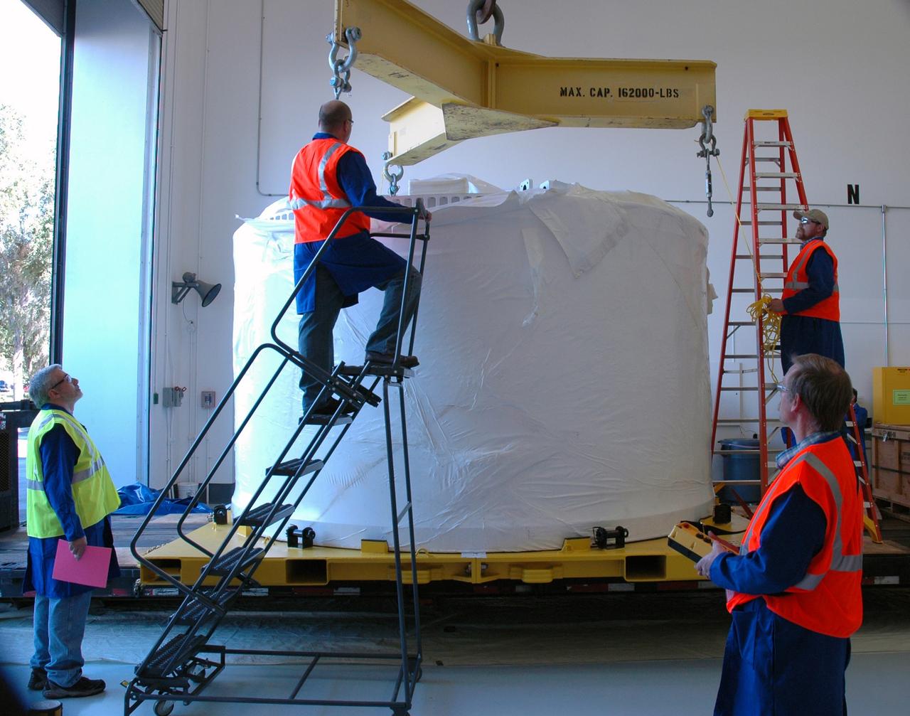 CAPE CANAVERAL, Fla. – Alliant Techsystems Inc. workers at Astrotech in Titusville, Fla., attach an overhead crane to the Ares I-X forward skirt just arrived from Major Tool & Machine Inc. in Indiana. The forward skirt will be lifted and moved to a stand. Major Tool is subcontractor to Ares I prime contractor Alliant Techsystems Inc., or ATK, in Utah. The forward skirt is the initial piece of first-stage hardware in preparation for the July 2009 test flight of the agency's next-generation spacecraft and launch vehicle system. Built entirely of armored steel, the 14,000-pound segment is seven feet tall and 12-1/4 feet wide. United Space Alliance, under a subcontract to ATK, will integrate and assemble the forward skirt components in the Assembly and Refurbishment Facility at NASA's Kennedy Space Center in Florida.. It will then be moved to the Vehicle Assembly Building high bay 3 for stacking operations. Photo credit: NASA/Tim Jacobs