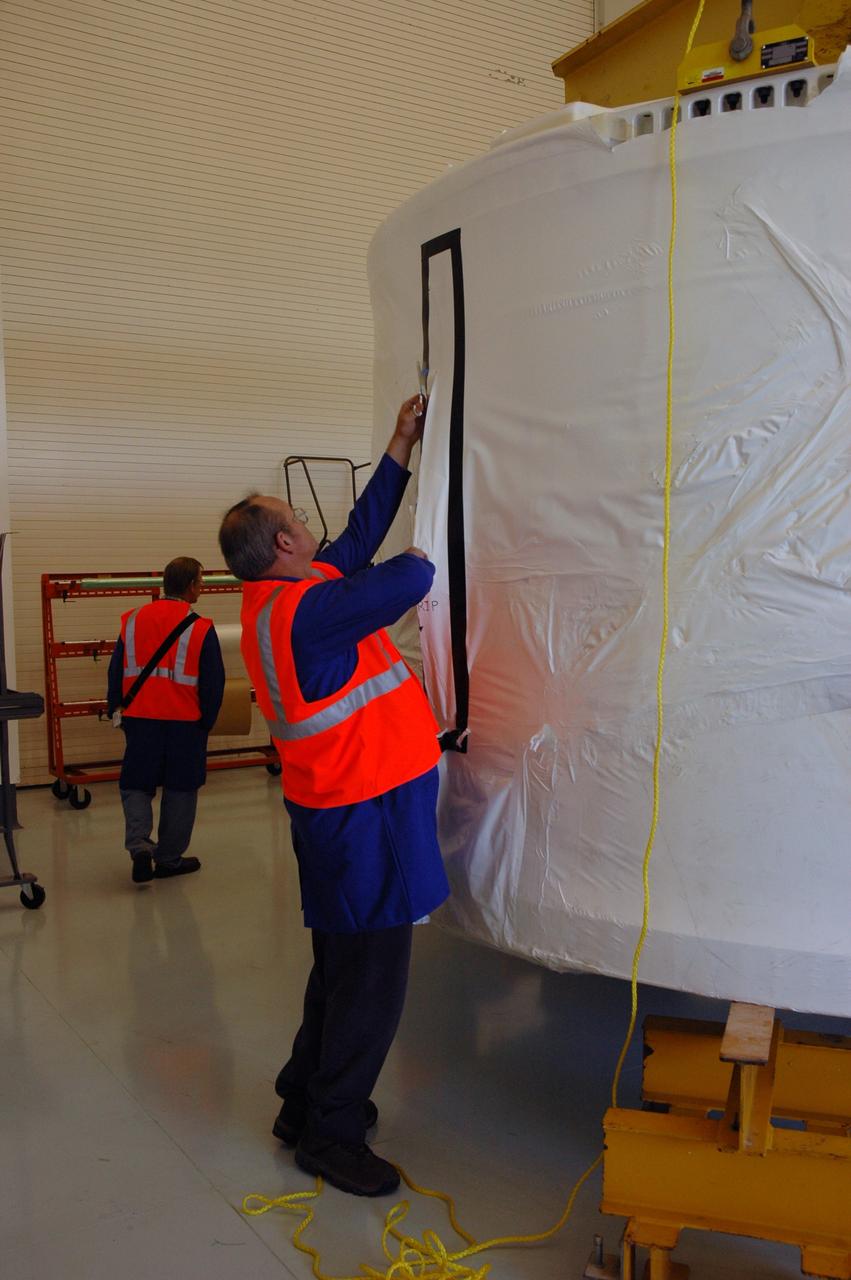 CAPE CANAVERAL, Fla. – Alliant Techsystems Inc. workers at Astrotech in Titusville, Fla., begin removing an internal cover from around the Ares I-X forward skirt. The hardware was delivered from Major Tool & Machine Inc. in Indiana. Major Tool is subcontractor to Ares I prime contractor Alliant Techsystems Inc., or ATK, in Utah. The forward skirt is the initial piece of first-stage hardware in preparation for the July 2009 test flight of the agency's next-generation spacecraft and launch vehicle system. Built entirely of armored steel, the 14,000-pound segment is seven feet tall and 12-1/4 feet wide. United Space Alliance, under a subcontract to ATK, will integrate and assemble the forward skirt components in the Assembly and Refurbishment Facility at NASA's Kennedy Space Center in Florida.. It will then be moved to the Vehicle Assembly Building high bay 3 for stacking operations. Photo credit: NASA/Tim Jacobs