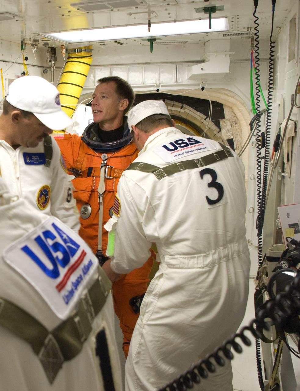 CAPE CANAVERAL, Fla. – In the White Room on Launch Pad 39A at NASA's Kennedy Space Center in Florida, STS-126 Commander Chris Ferguson is helped by suit technicians to put on a harness over his launch and entry suit. In the background is the hatch for entry into space shuttle Endeavour. STS-126 is the 124th space shuttle flight and the 27th flight to the International Space Station. The mission will feature four spacewalks and work that will prepare the space station to house six crew members for long- duration missions.  Liftoff is scheduled for 7:55 p.m. EST Nov. 14.   Photo credit: NASA/Sandra Joseph-Kevin O'Connell