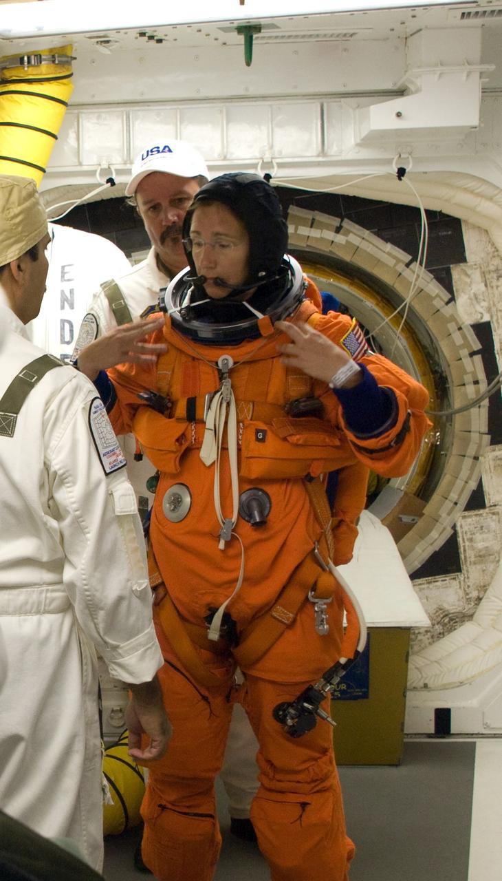 CAPE CANAVERAL, Fla. – In the White Room on Launch Pad 39A at NASA's Kennedy Space Center in Florida, STS-126 Mission Specialist Sandra Magnus is helped by suit technicians to put on a harness over her launch and entry suit. In the background is the hatch for entry into space shuttle Endeavour. STS-126 is the 124th space shuttle flight and the 27th flight to the International Space Station. The mission will feature four spacewalks and work that will prepare the space station to house six crew members for long- duration missions.  Liftoff is scheduled for 7:55 p.m. EST Nov. 14.   Photo credit: NASA/Sandra Joseph-Kevin O'Connell