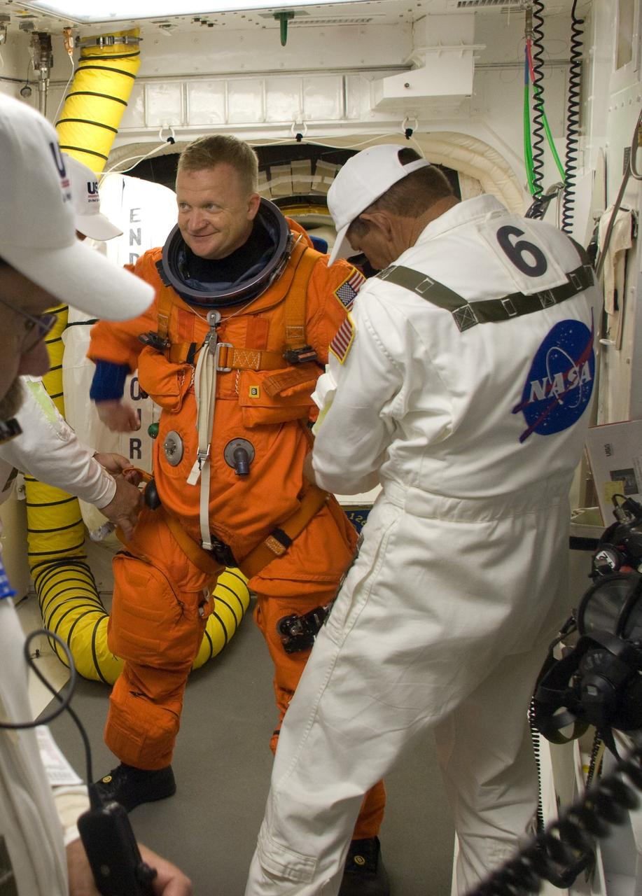 CAPE CANAVERAL, Fla. – In the White Room on Launch Pad 39A at NASA's Kennedy Space Center in Florida, STS-126 Pilot Eric Boe is helped by suit technicians to put on a harness over his launch and entry suit. In the background is the hatch for entry into space shuttle Endeavour. STS-126 is the 124th space shuttle flight and the 27th flight to the International Space Station. The mission will feature four spacewalks and work that will prepare the space station to house six crew members for long- duration missions. Liftoff is scheduled for 7:55 p.m. EST Nov. 14. Photo credit: NASA/Sandra Joseph-Kevin O'Connell