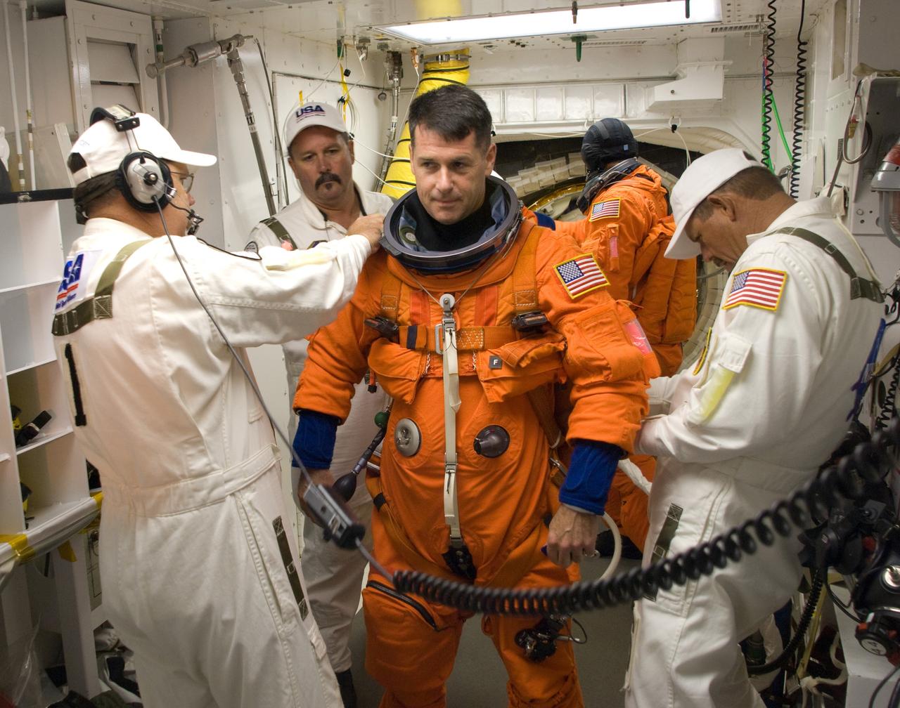 CAPE CANAVERAL, Fla. – In the White Room on Launch Pad 39A at NASA's Kennedy Space Center in Florida, STS-126 Mission Specialist Shane Kimbrough is helped by suit technicians to get into his harness. In the background is another crew member waiting to enter space shuttle Endeavour. STS-126 is the 124th space shuttle flight and the 27th flight to the International Space Station. The mission will feature four spacewalks and work that will prepare the space station to house six crew members for long- duration missions. Liftoff is scheduled for 7:55 p.m. EST Nov. 14. Photo credit: NASA/Sandra Joseph-Kevin O'Connell