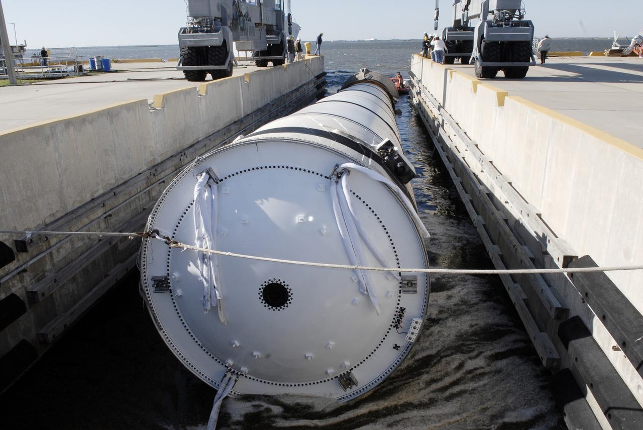 CAPE CANAVERAL, Fla. –   At the dock at Hangar AF at Cape Canaveral Air Force Station in Florida, the spent solid rocket booster from space shuttle Endeavour's launch Nov. 14 on mission STS-126 is moved to an area beneath the straddle crane that will lift it out of the water.  The space shuttle’s solid rocket booster casings and associated flight hardware are recovered at sea. The spent rocket was recovered by NASA's Solid Rocket Booster Retrieval Ship Freedom Star.  The boosters impact the Atlantic Ocean approximately seven minutes after liftoff. The splashdown area is a square of about six by nine nautical miles located about 140 nautical miles downrange from the launch pad. The retrieval ships are stationed approximately 8 to 10 nautical miles from the impact area at the time of splashdown. As soon as the boosters enter the water, the ships accelerate to a speed of 15 knots and quickly close on the boosters. The pilot chutes and main parachutes are the first items to be brought on board. With the chutes and frustum recovered, attention turns to the boosters. The ship’s tow line is connected and the booster is returned to the Port and, after transfer to a position alongside the ship, to Hangar AF. There, the expended boosters are disassembled, refurbished and reloaded with solid propellant for reuse. Photo credit: NASA/Kim Shiflett