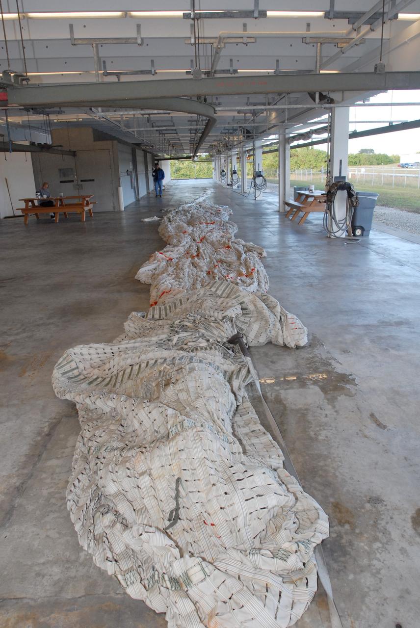 CAPE CANAVERAL, Fla. –   Parachutes recovered from sea after the launch of space shuttle Endeavour on the STS-126 mission are stretched out at the Parachute Refurbishment Facility at NASA's Kennedy Space Center in Florida to detangle them.  The parachutes are used to slow the descent of the solid rocket boosters that are jettisoned during liftoff.  After the chutes are returned to the facility following launch, a hanging monorail system is used to transport each parachute into a 30,000-gallon washer and then into a huge dryer heated with 140-de¬gree air at 13,000 cubic feet per minute.  One pilot, one drogue and three main canopies per booster slow the booster’s fall from about 360 mph to 50 mph.  After the chutes are cleaned and repaired, they must be care¬fully packed into their bags so they will deploy correctly the next time they are used. Photo credit: NASA/Jim Grossmann