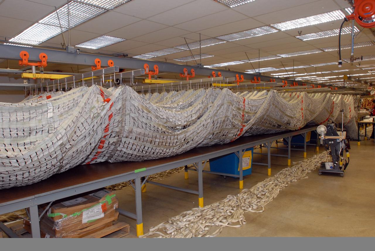 CAPE CANAVERAL, Fla. –    Parachutes recovered from sea after the launch of space shuttle Endeavour on the STS-126 mission are suspended from a hanging monorail system at the Parachute Refurbishment Facility at NASA's Kennedy Space Center in Florida. The parachutes are used to slow the descent of the solid rocket boosters that are jettisoned during liftoff.  The monorail will transport each parachute into a 30,000-gallon washer and a huge dryer heated with 140-degree air at 13,000 cubic feet per minute. One pilot, one drogue and three main canopies per booster slow the booster’s fall from about 360 mph to 50 mph.  After the chutes are cleaned and repaired, they must be carefully packed into their bags so they will deploy correctly the next time they are used. Photo credit: NASA/Jim Grossmann