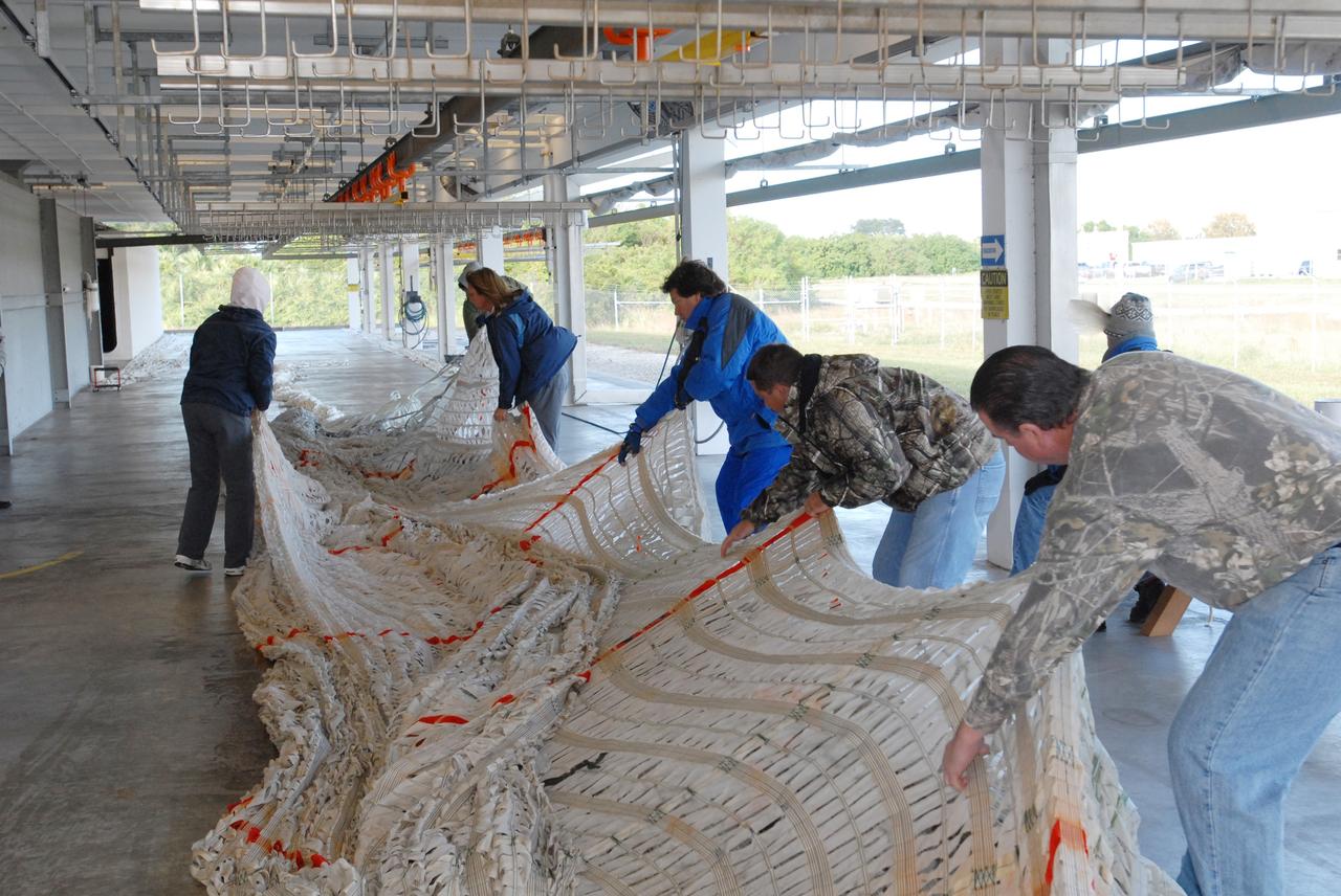 CAPE CANAVERAL, Fla. –  At the Parachute Refurbishment Facility at NASA's Kennedy Space Center in Florida, workers spread out the parachutes recovered from sea after the launch of space shuttle Endeavour on the STS-126 mission to detangle them. The parachutes are used to slow the descent of the solid rocket boosters that are jettisoned during liftoff. One pilot, one drogue and three main canopies per booster slow the booster’s fall from about 360 mph to 50 mph.  After the chutes are cleaned and repaired, they must be carefully packed into their bags so they will deploy correctly the next time they are used. Photo credit: NASA/Jim Grossmann
