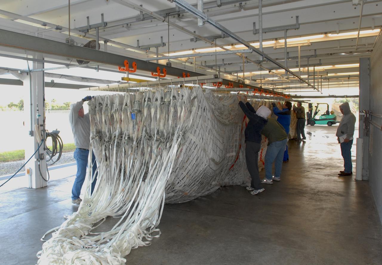 CAPE CANAVERAL, Fla. – At the Parachute Refurbishment Facility at NASA's Kennedy Space Center in Florida, workers begin hanging the parachutes recovered from sea after the launch of space shuttle Endeavour on the STS-126 mission onto a monorail system. The parachutes are used to slow the descent of the solid rocket boosters that are jettisoned during liftoff. The monorail will transport each parachute into a 30,000-gallon washer and a huge dryer heated with 140-degree air at 13,000 cubic feet per minute. One pilot, one drogue and three main canopies per booster slow the booster’s fall from about 360 mph to 50 mph. After the chutes are cleaned and repaired, they must be carefully packed into their bags so they will deploy correctly the next time they are used. Photo credit: NASA/Jim Grossmann